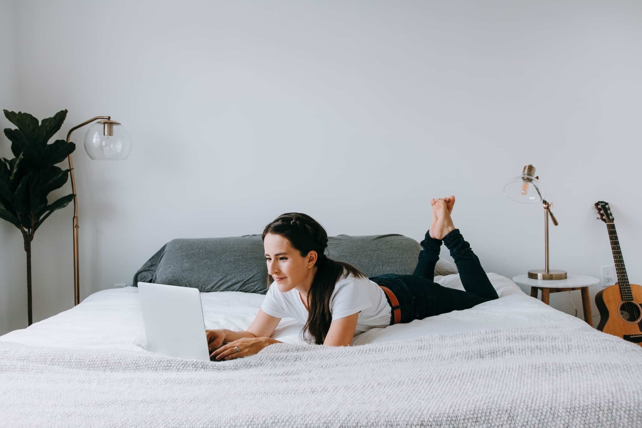 rapariga deitada na cama com o portátil