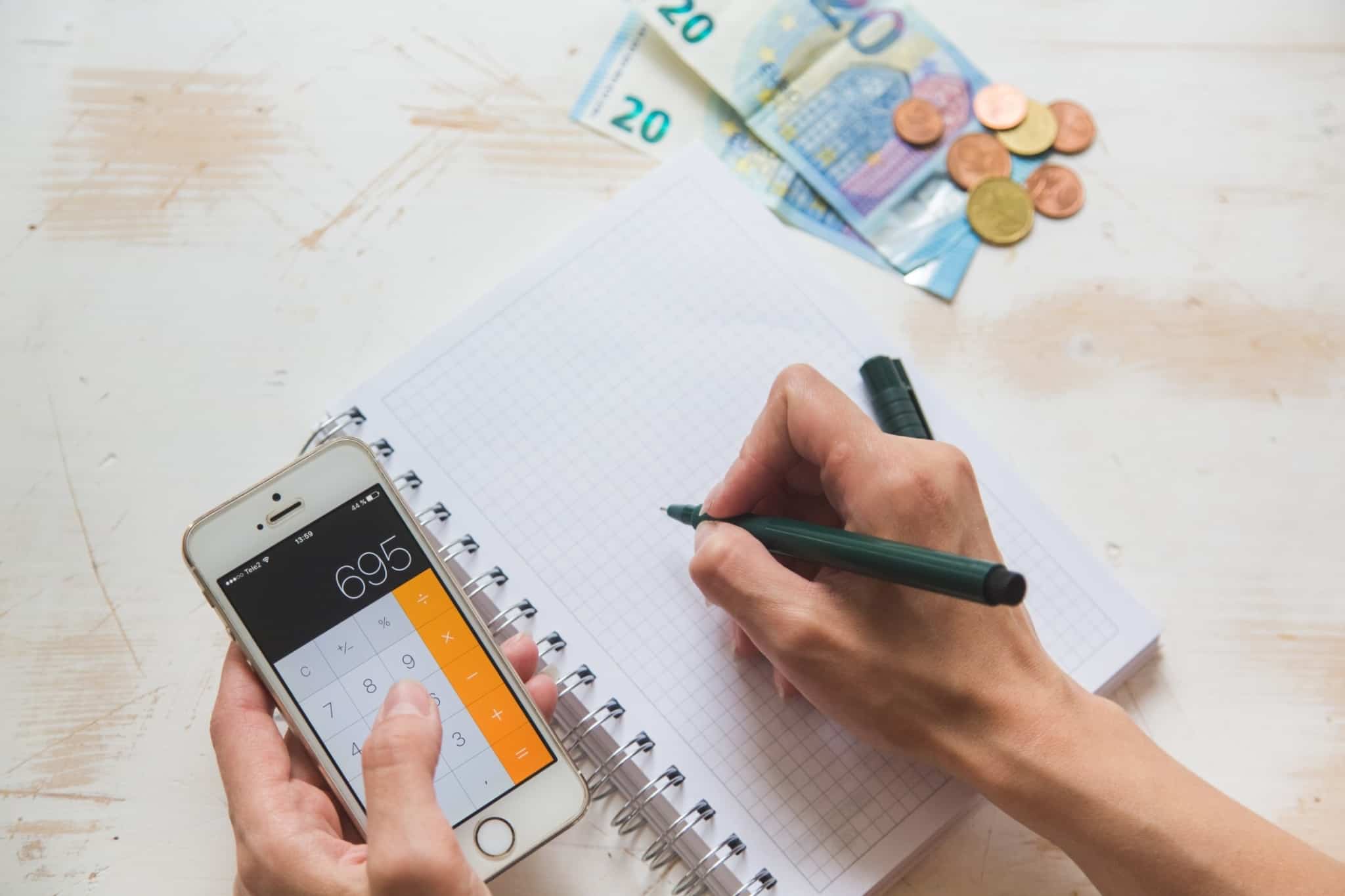 pessoa faz as contas na calculadora e com notas de euros ao lado