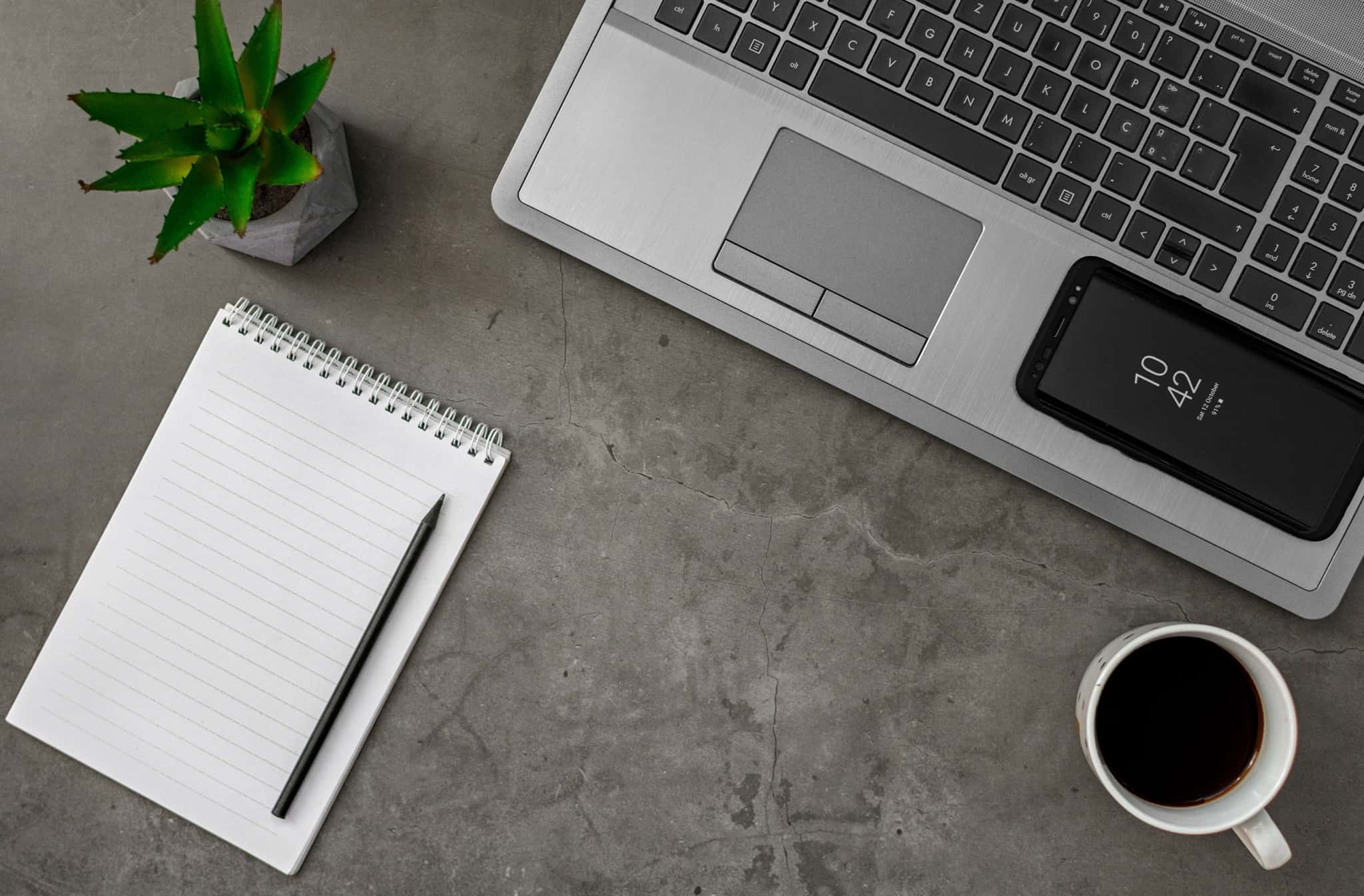 secretária com portatil bloco de notas e uma chavena de cafe