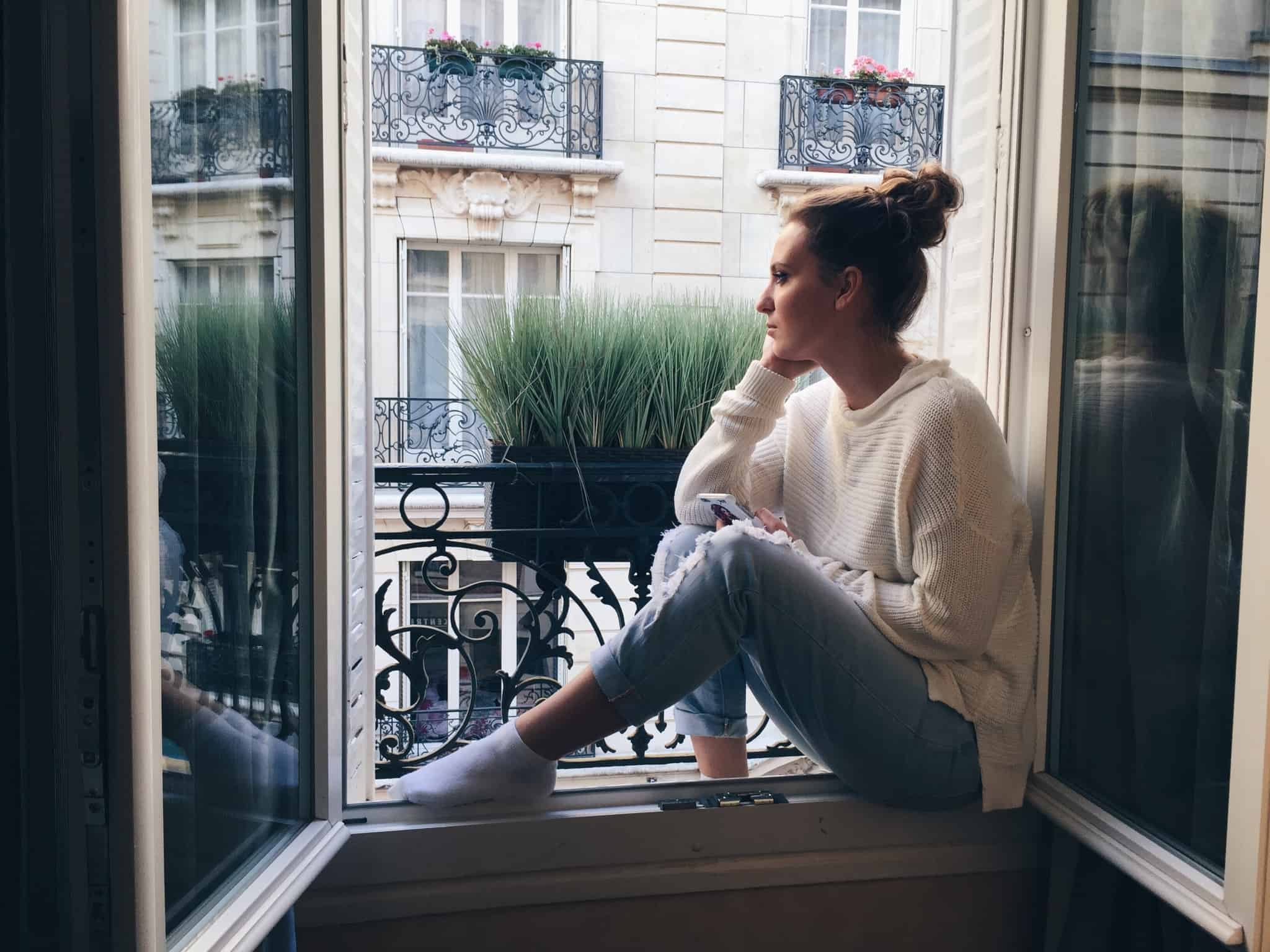 Preços das casas aumentaram quase 10% em 2019 mulher sentada à janela de casa