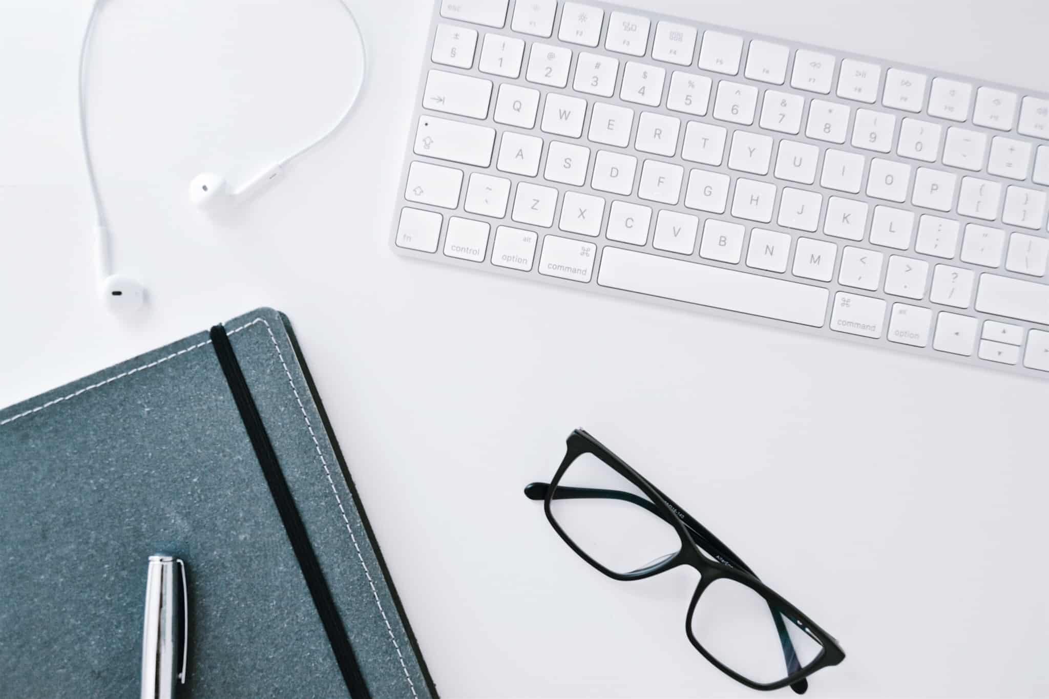 imac com caderno de notas caneta e oculos