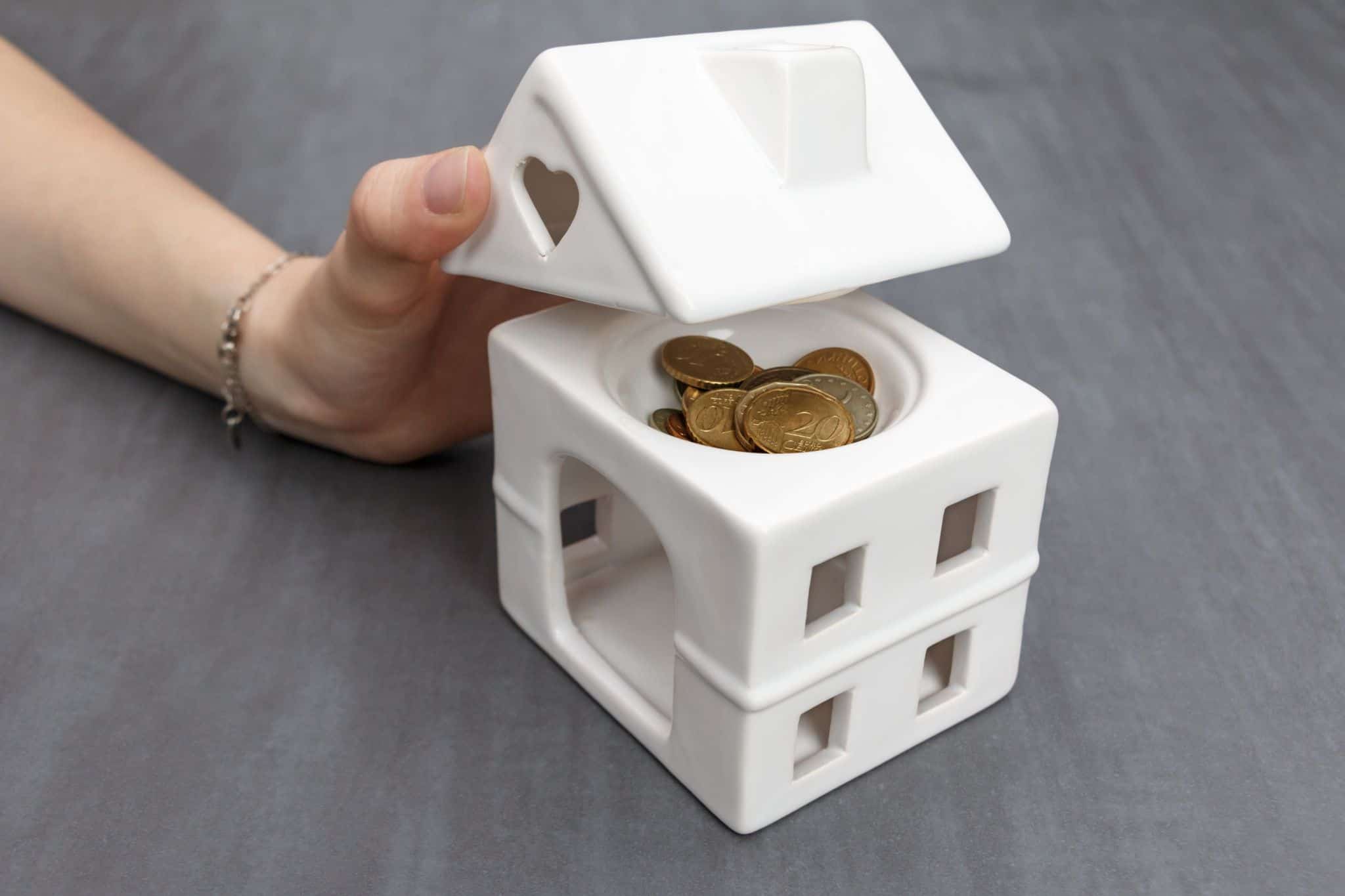 casa em miniatura com moedas lá dentro