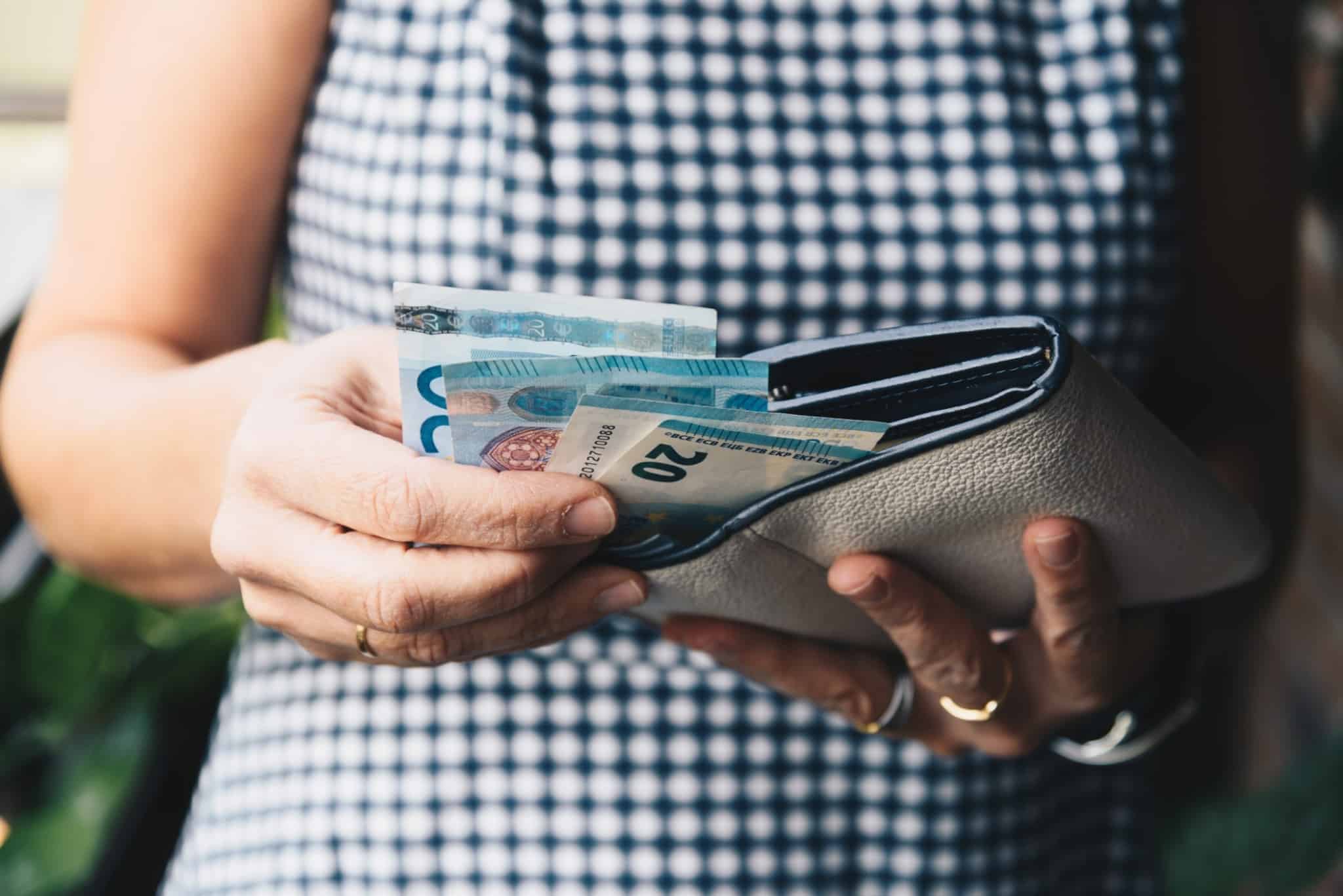 Mulher a guardar notas de 20 euros na carteiras