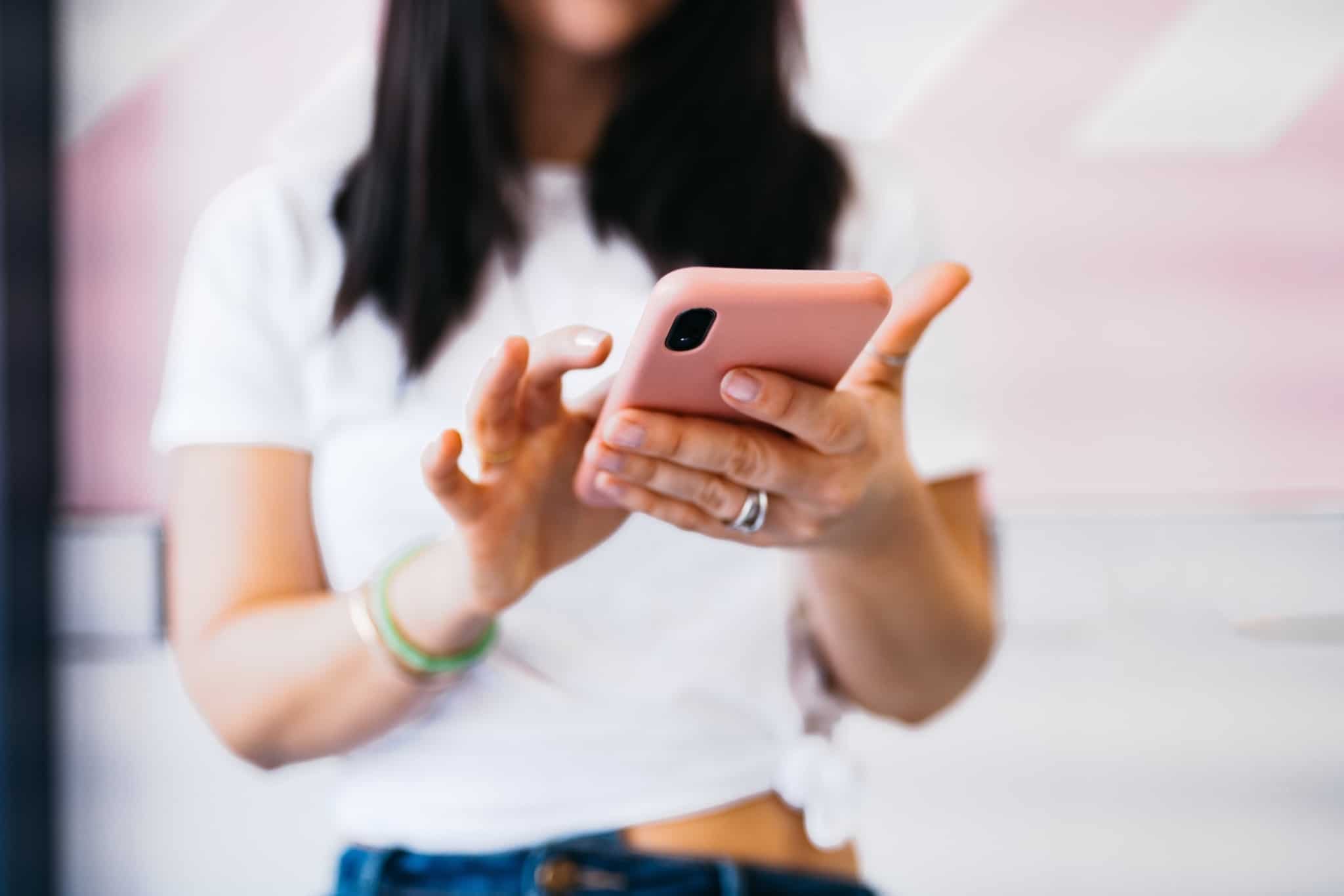 mulher a segurar no telemóvel de capa cor de rosa
