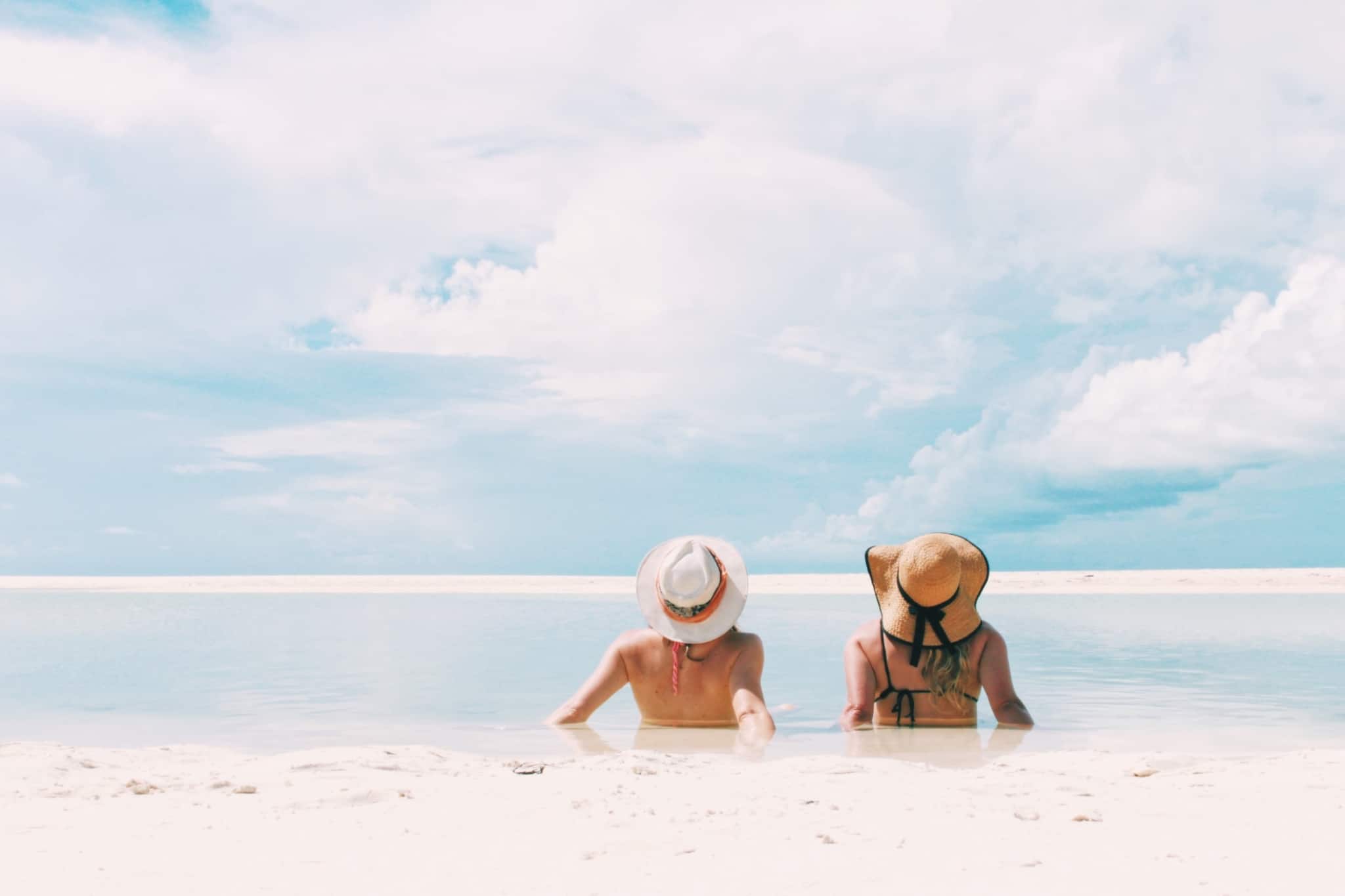 duas mulheres sentadas na areia a olhar para o mar