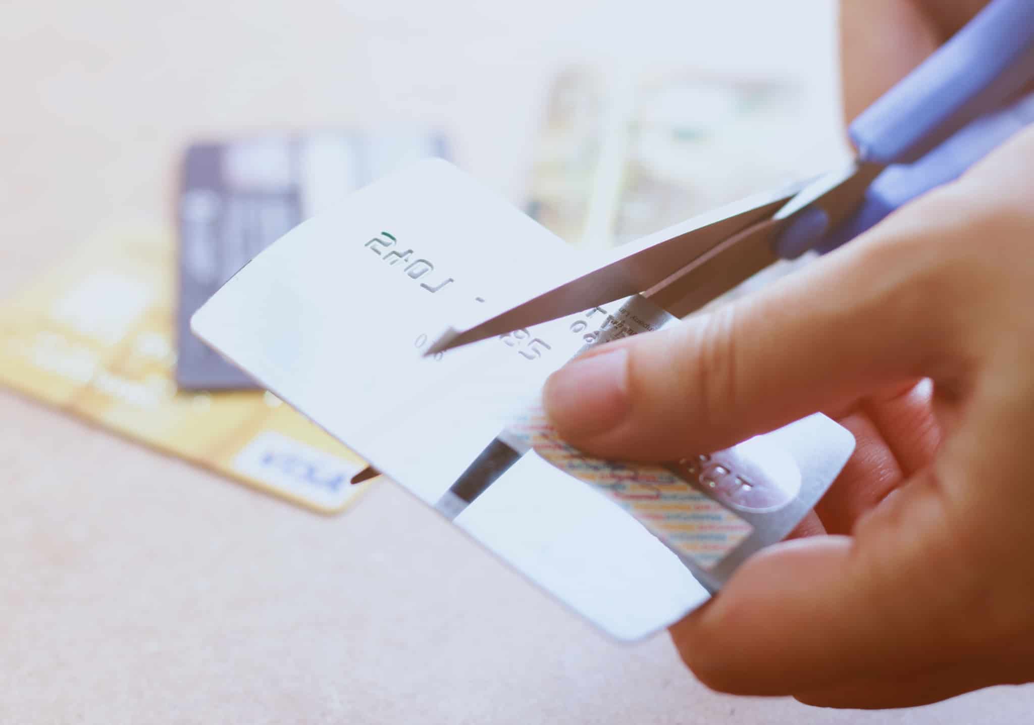 mão a cortar um cartão de crédito