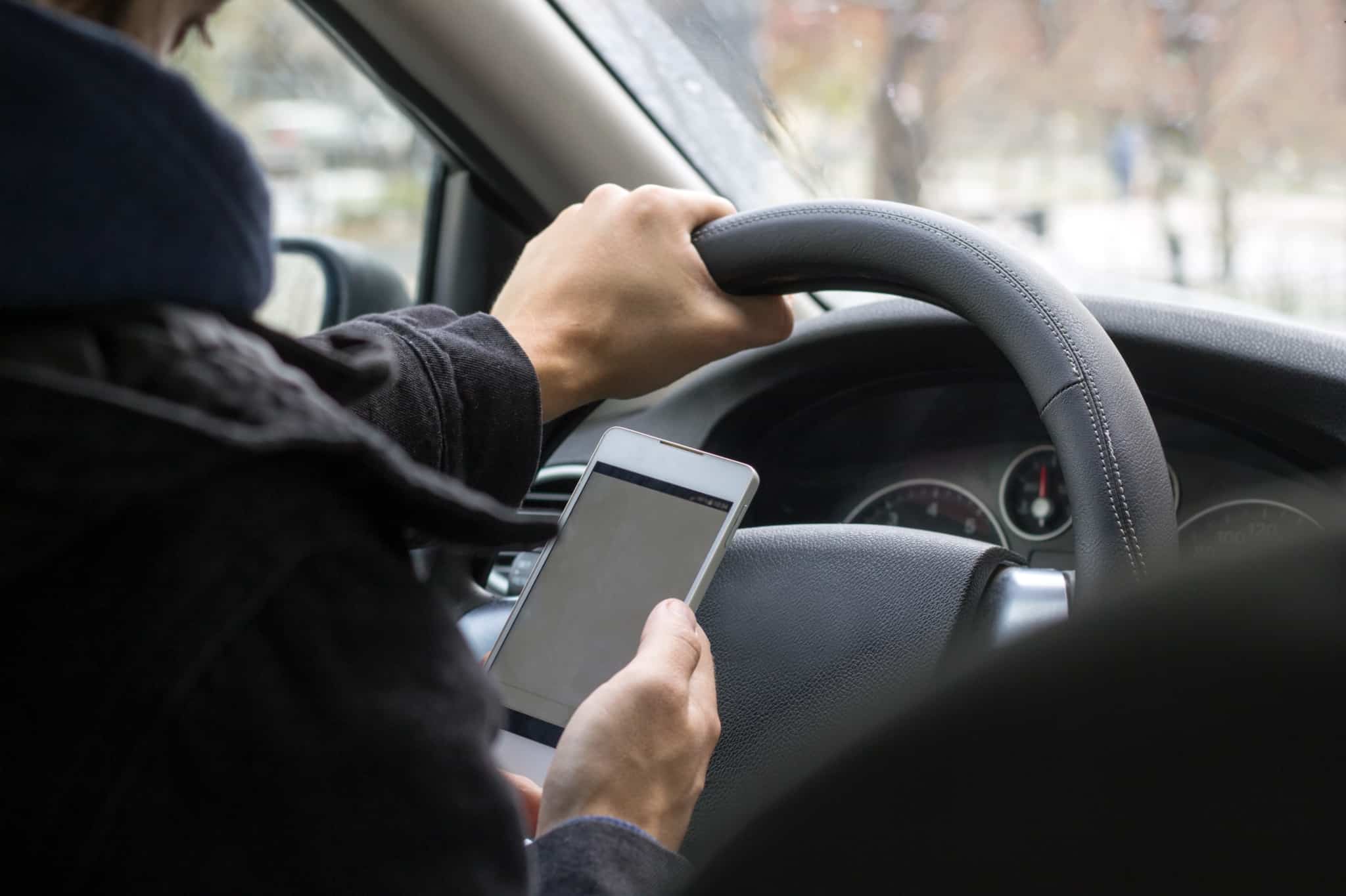 Homem usa o telemóvel enquanto conduz