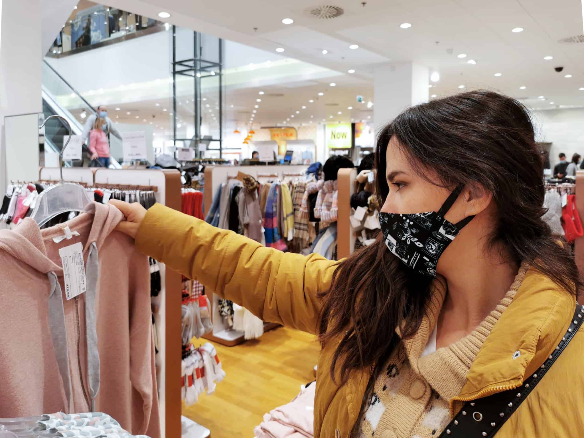 Rapariga pega numa camisola cor de rosa que está pendurada na loja
