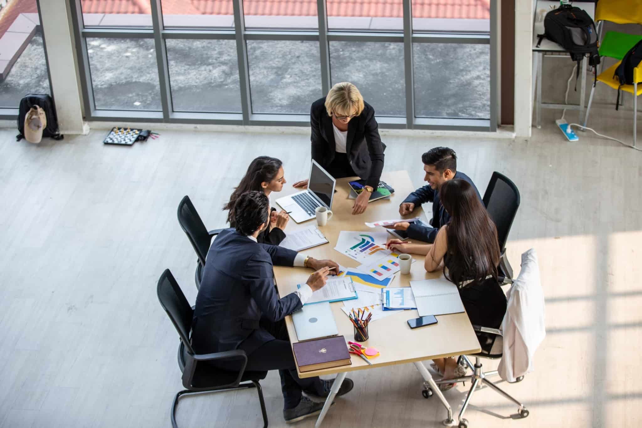 Quatro pessoas reunidas em torno de uma mesa com muita documentação em cima a ilustrar o que significa um contrato coletivo de trabalho