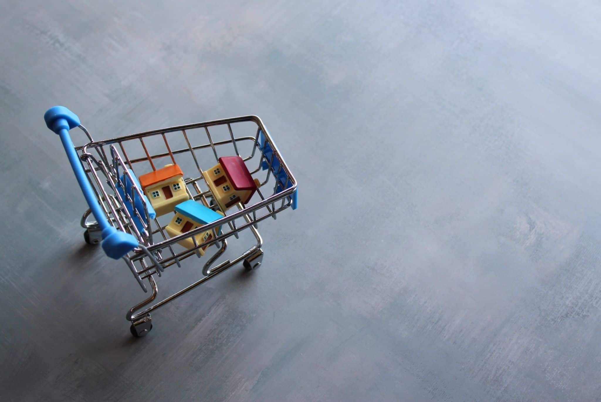 Carrinho de supermercado de brincar com casinhas lá dentro a evocar crédito à habitação
