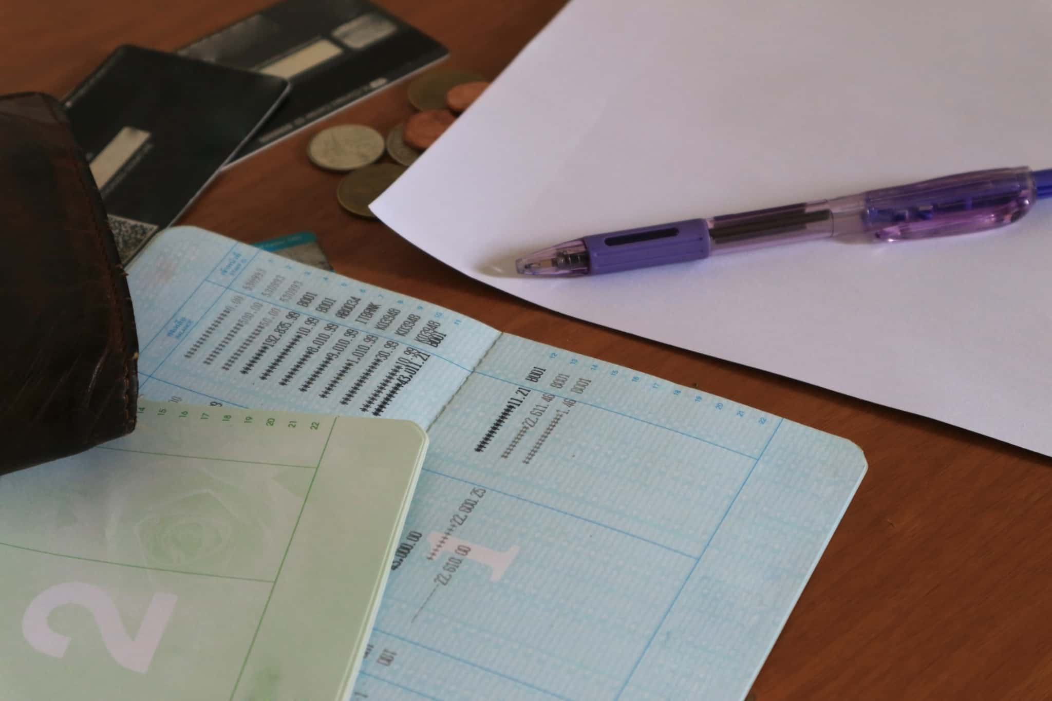 mesa com caderneta com registo de mvimentos e saldos, e papel e caneta para verificar as contas.