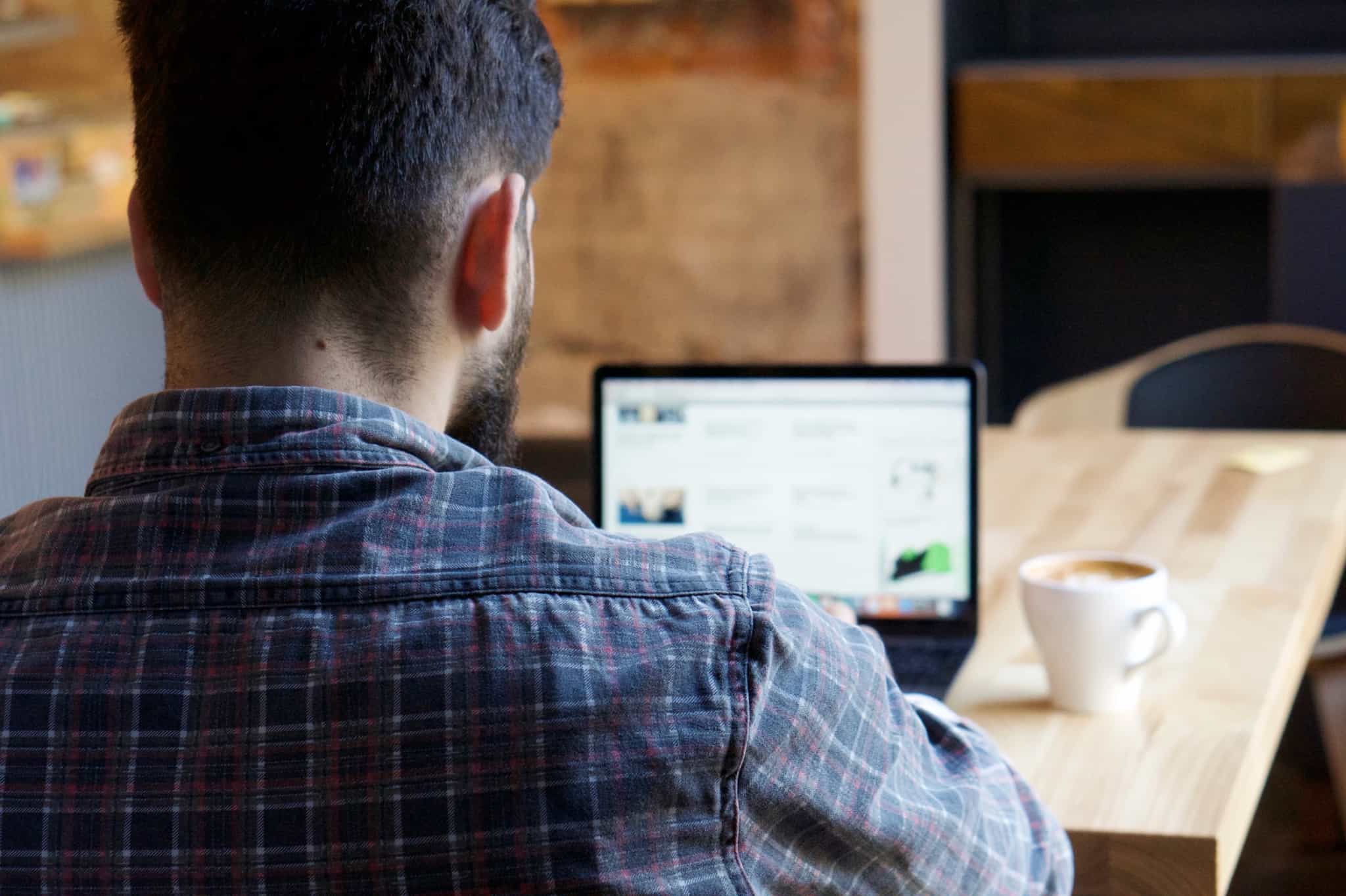 jovem rapaz está a trabalhar no seu computador portátil, produzindo os seus conteúdos para a internet. Estes podem ser protegidos com as licenças Creative Commons