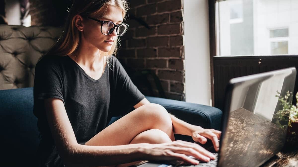 Rapariga sentada num sofá ao computador