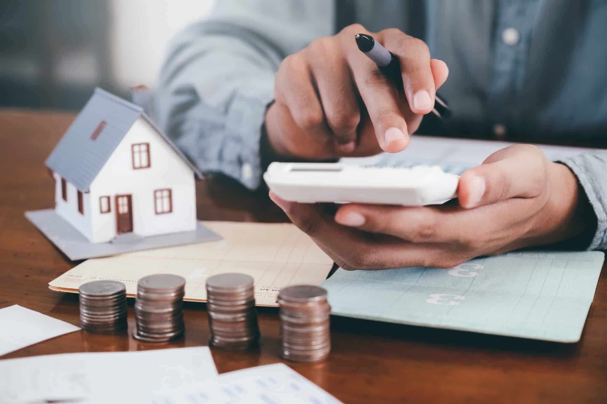 Jovem com 30 anos faz contas numa calculadora com os custos de comprar casa