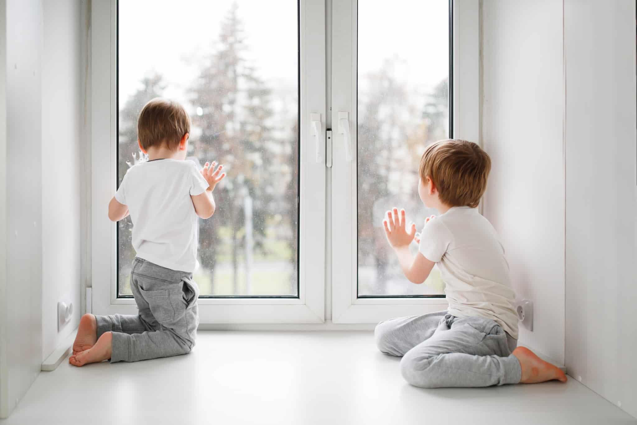 dois meninos, espreitam pela janela, numa casa segura para si