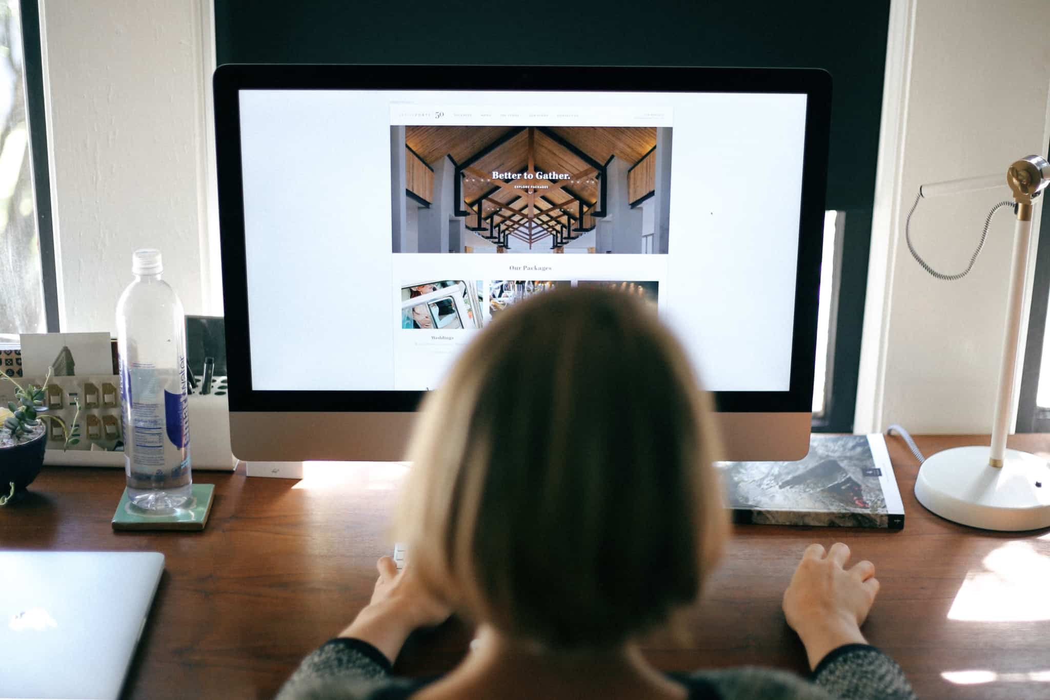 jovem mulher está ao computador, apoiada por um grande ecran, a criar e desenvolver um site para promover um negócio, uma marca.