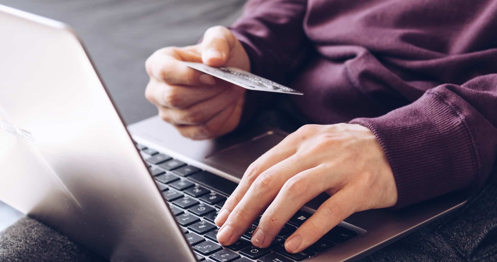 Rapaz com portátil ao colo e cartão na mão a levantar dinheiro online de apostas