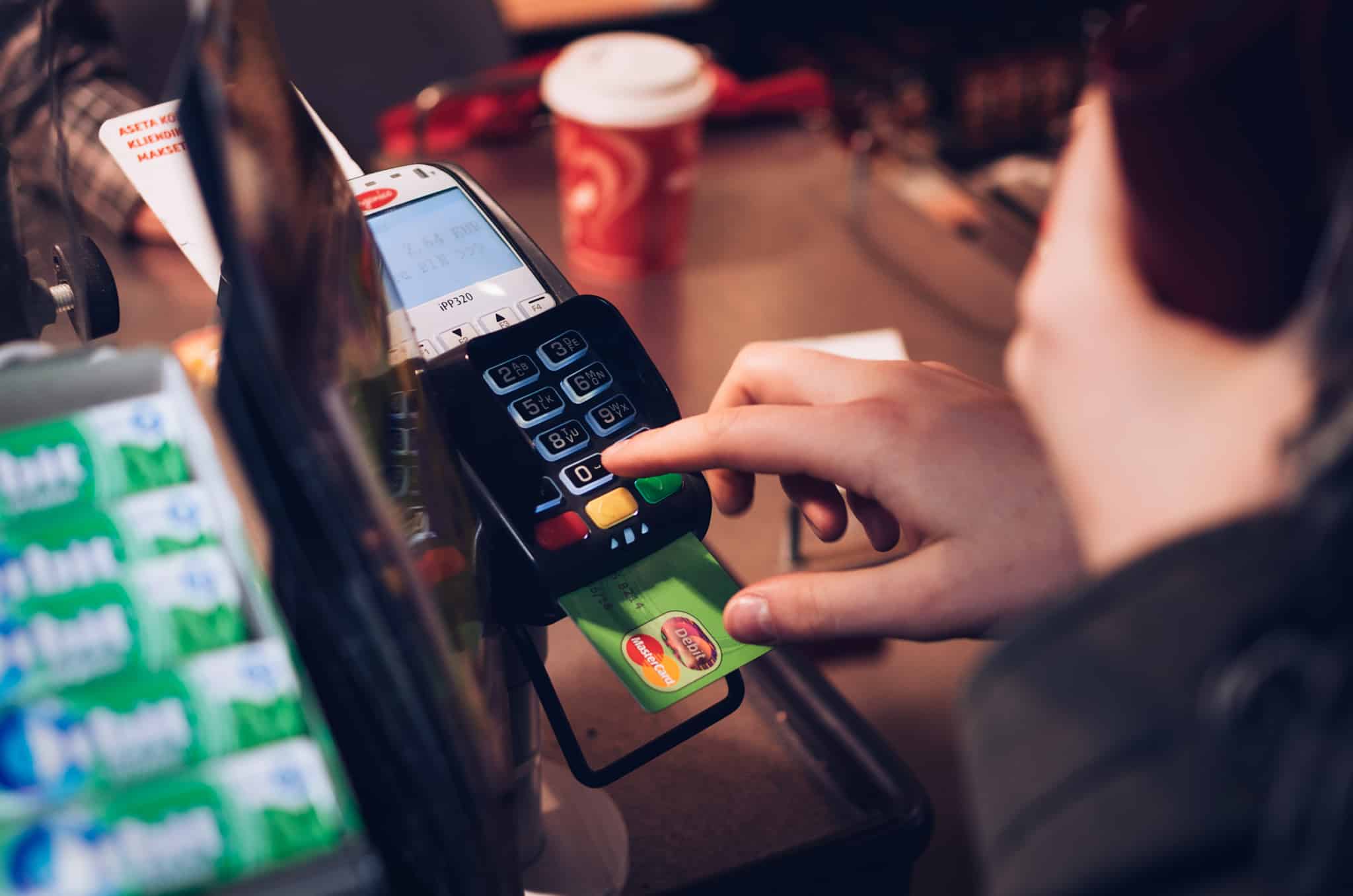 mão de jovem a digitar o código num TPA enqaunto faz um pagamento na Europa