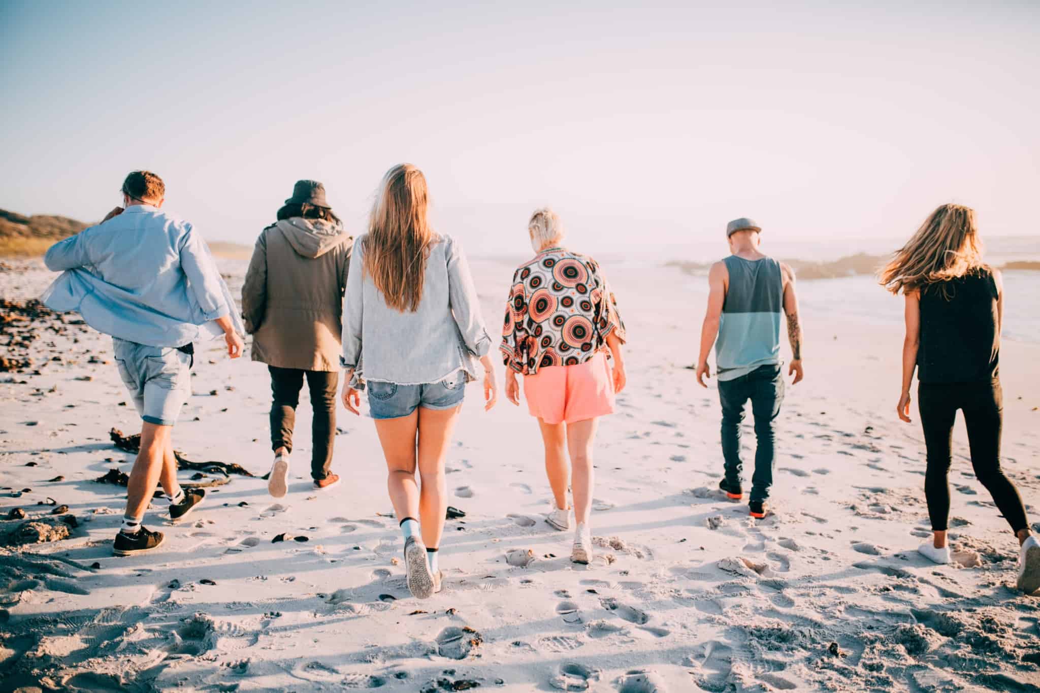 grupo de jovens estudantes, numa fase da vida em que as dicas financeiras podem fazer toda a diferença, correm pelo areal da praia