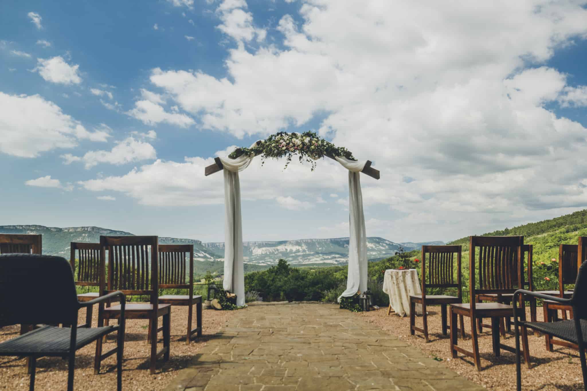licença de casamento ilustrada com a foto de um altar criado ao ar livre, rodeado de cadeiras para quem assiste, localizado no topo de uma zona verde e com um céu azul e algumas nuvens de fundo