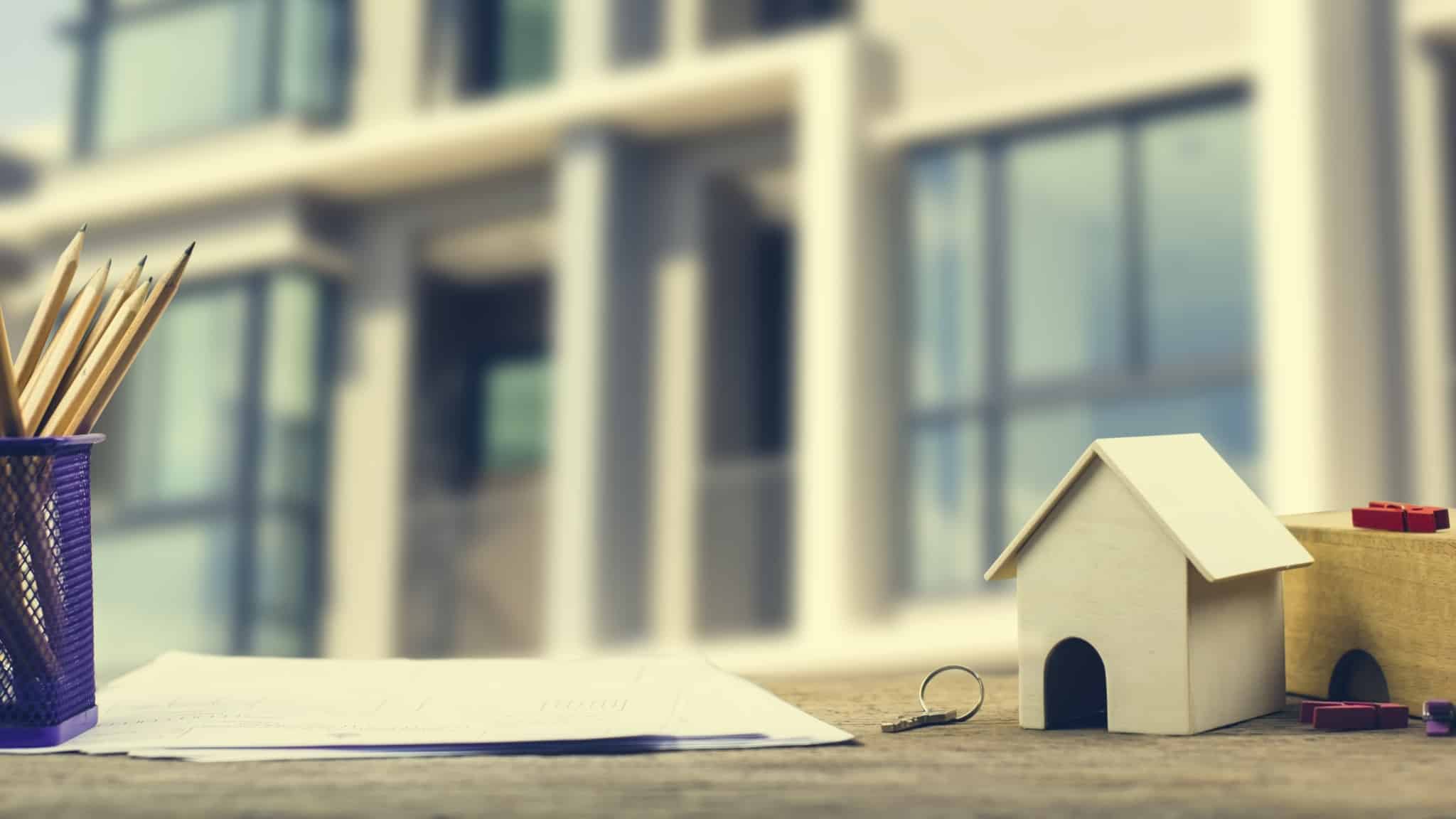 miniatura de casa pousada ao lado de um contrato de crédito habitação