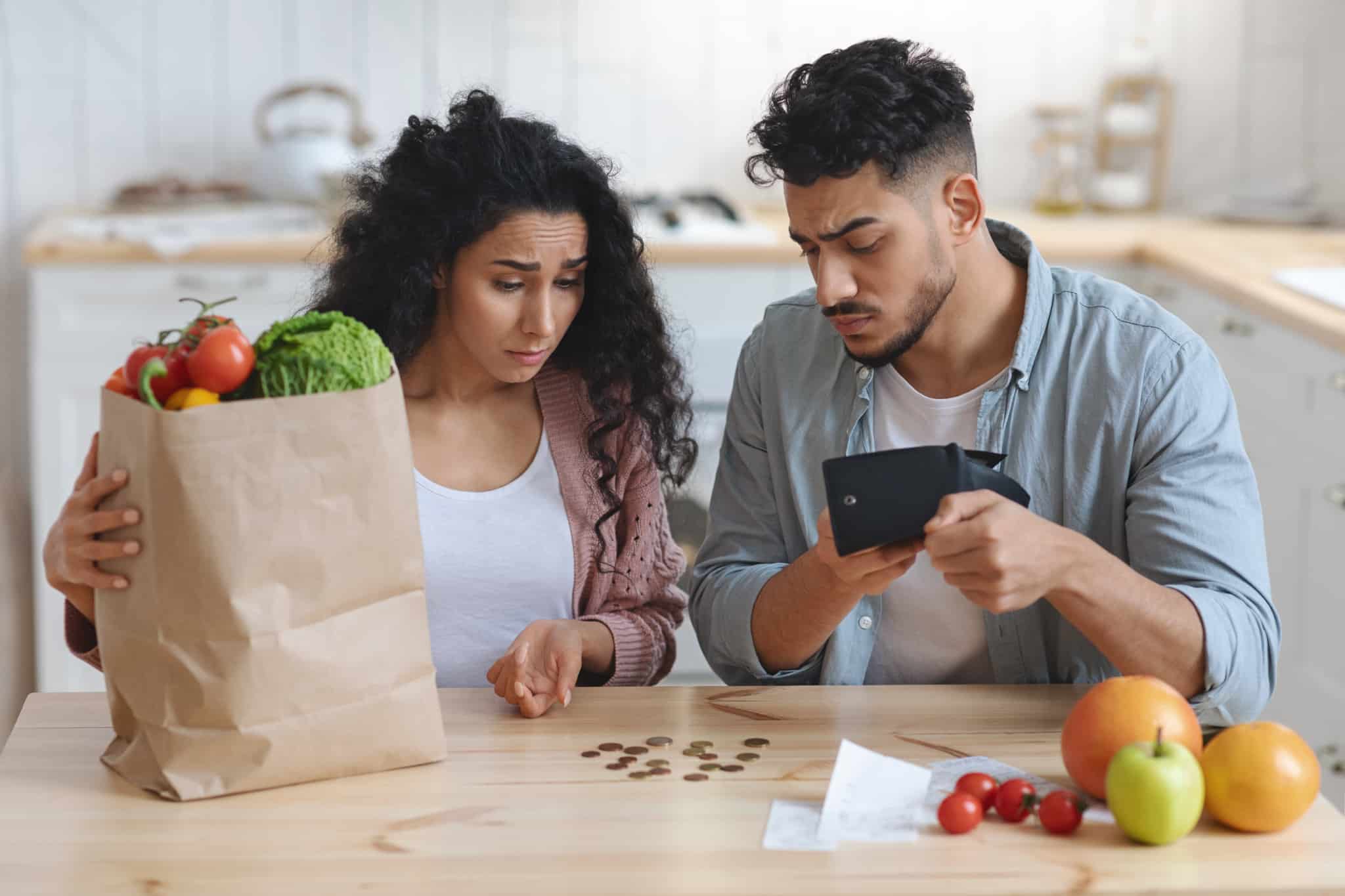 casal de jovens faz contas aos trocos, carregando um saco de compras, remetendo para as famílias carenciadas