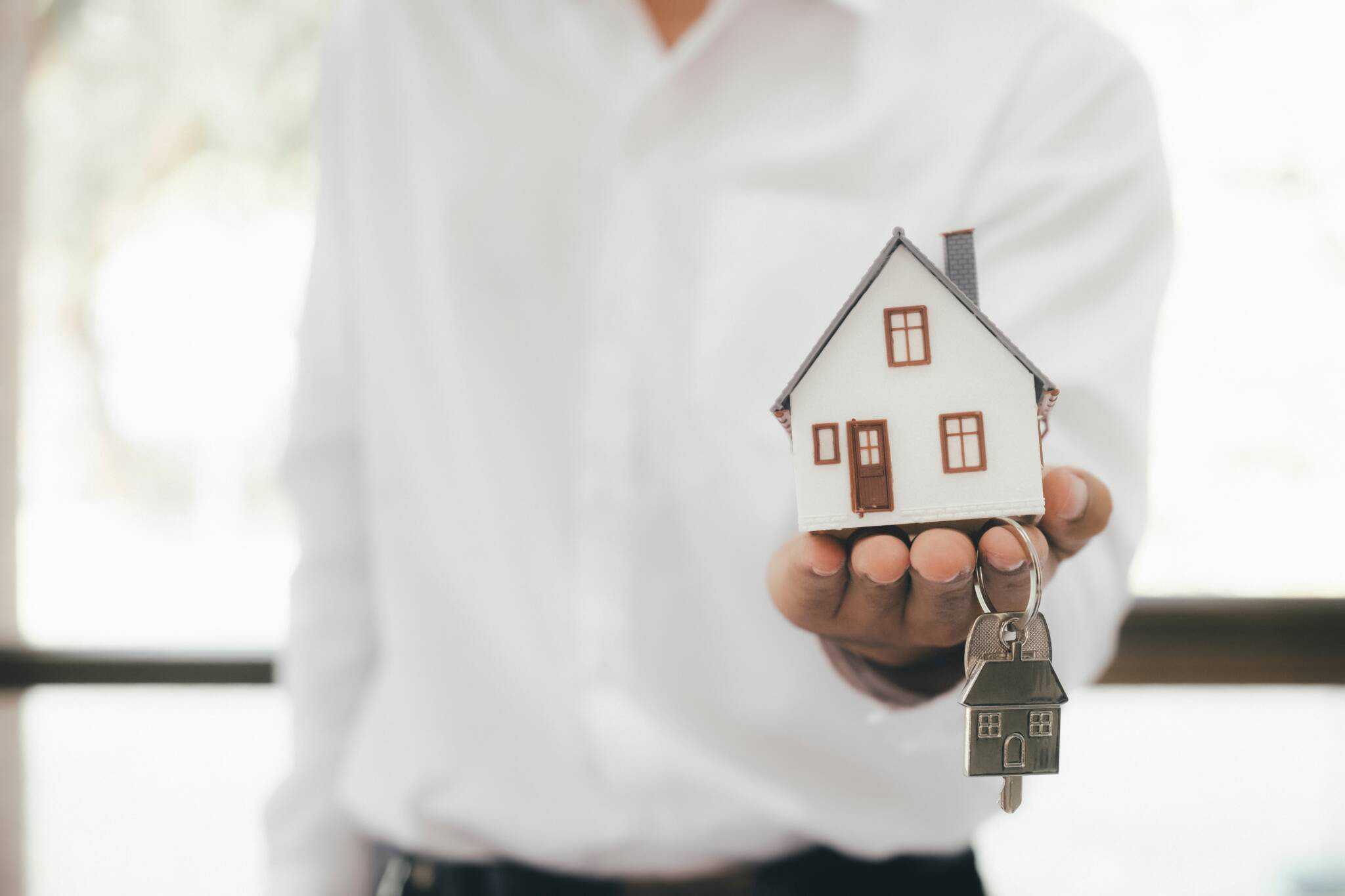 Pessoa a segurar as chaves e uma casa na mão após comprar casa em Portugal