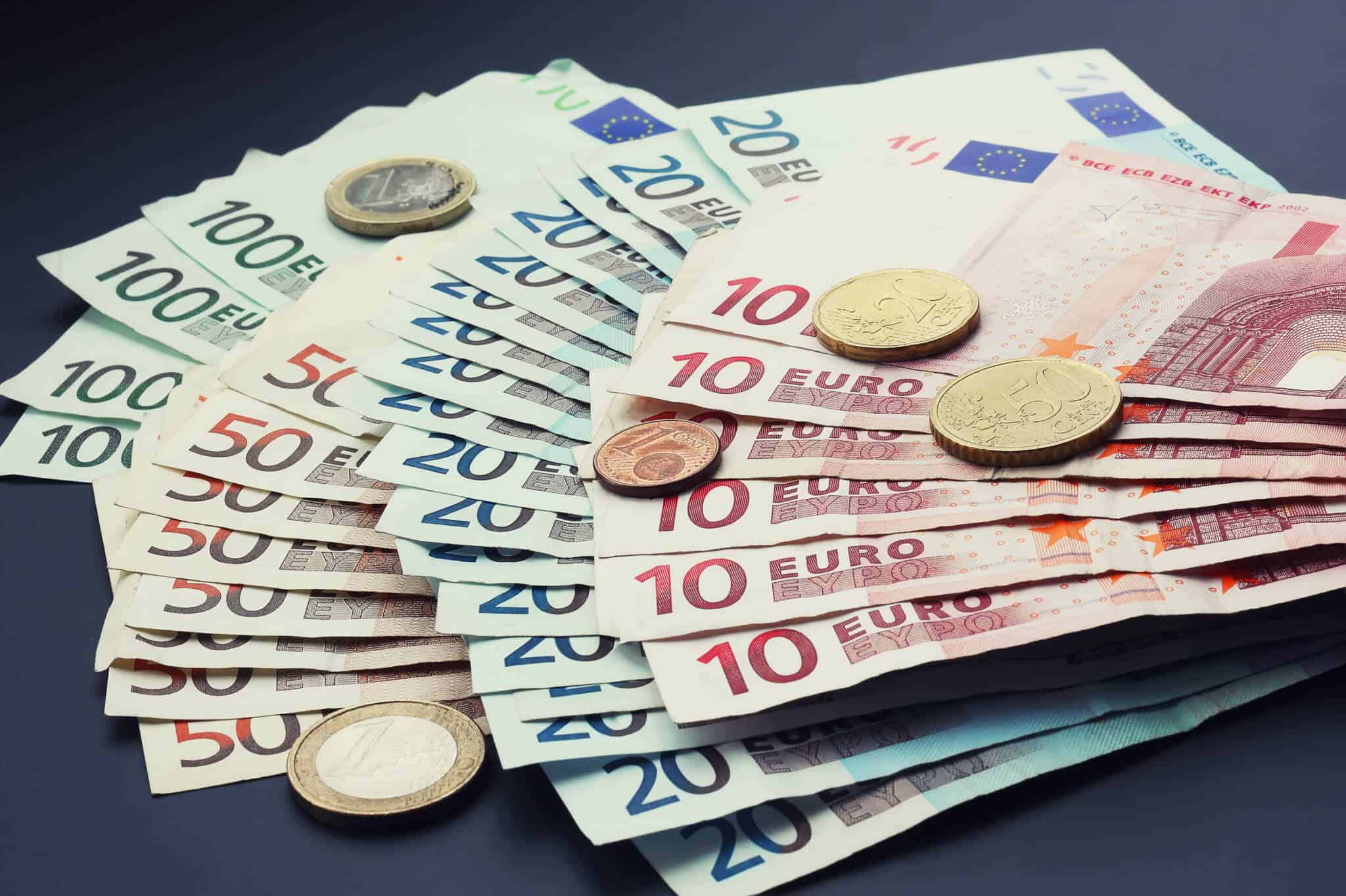 molho de notas e algumas moedas de Euro ilustram a possível desvalorização do euro e o seu impacto