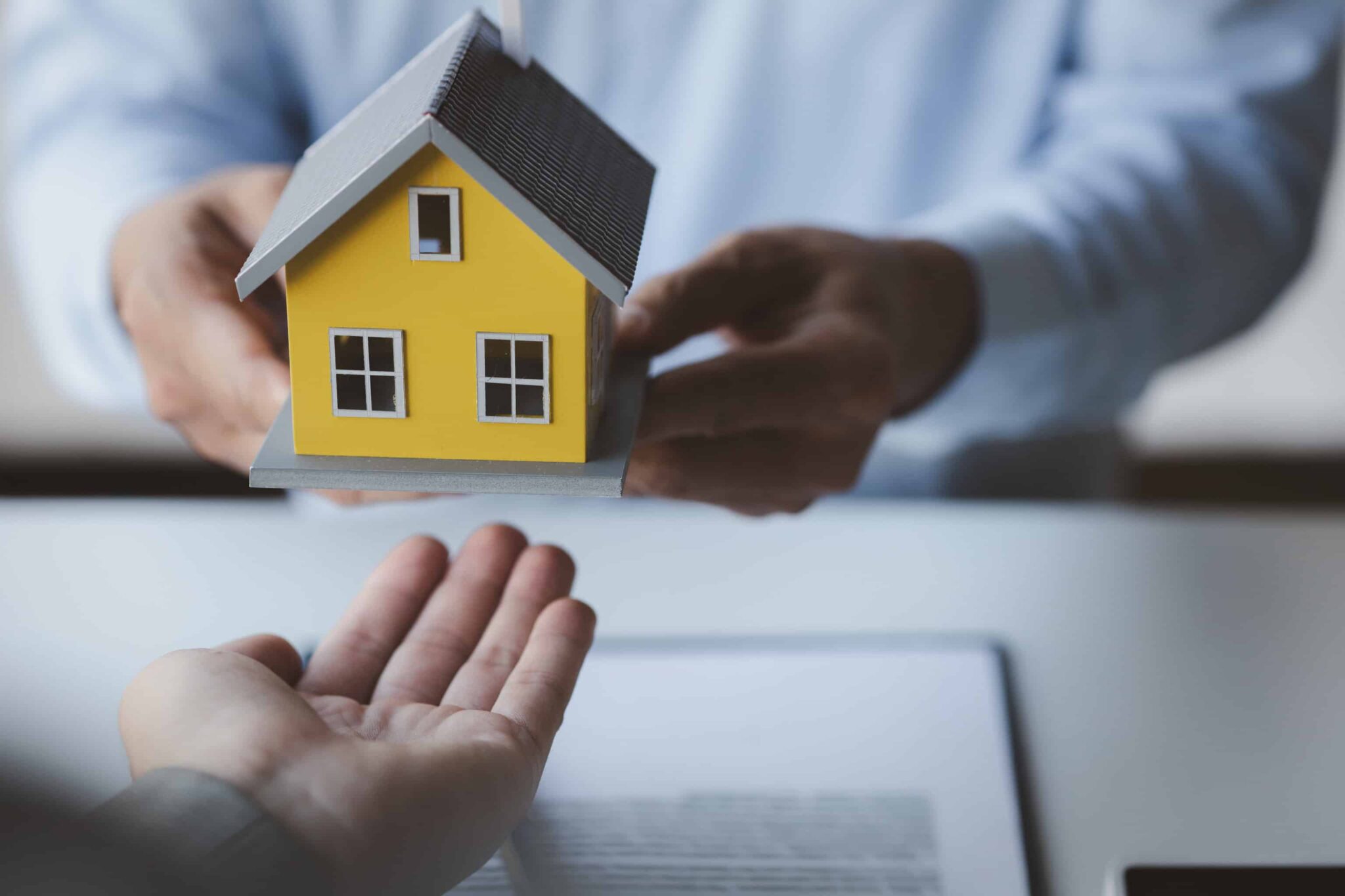 duas pessoas a passar uma casa para a outra a representar o crédito multiopções com reforço hipotecário