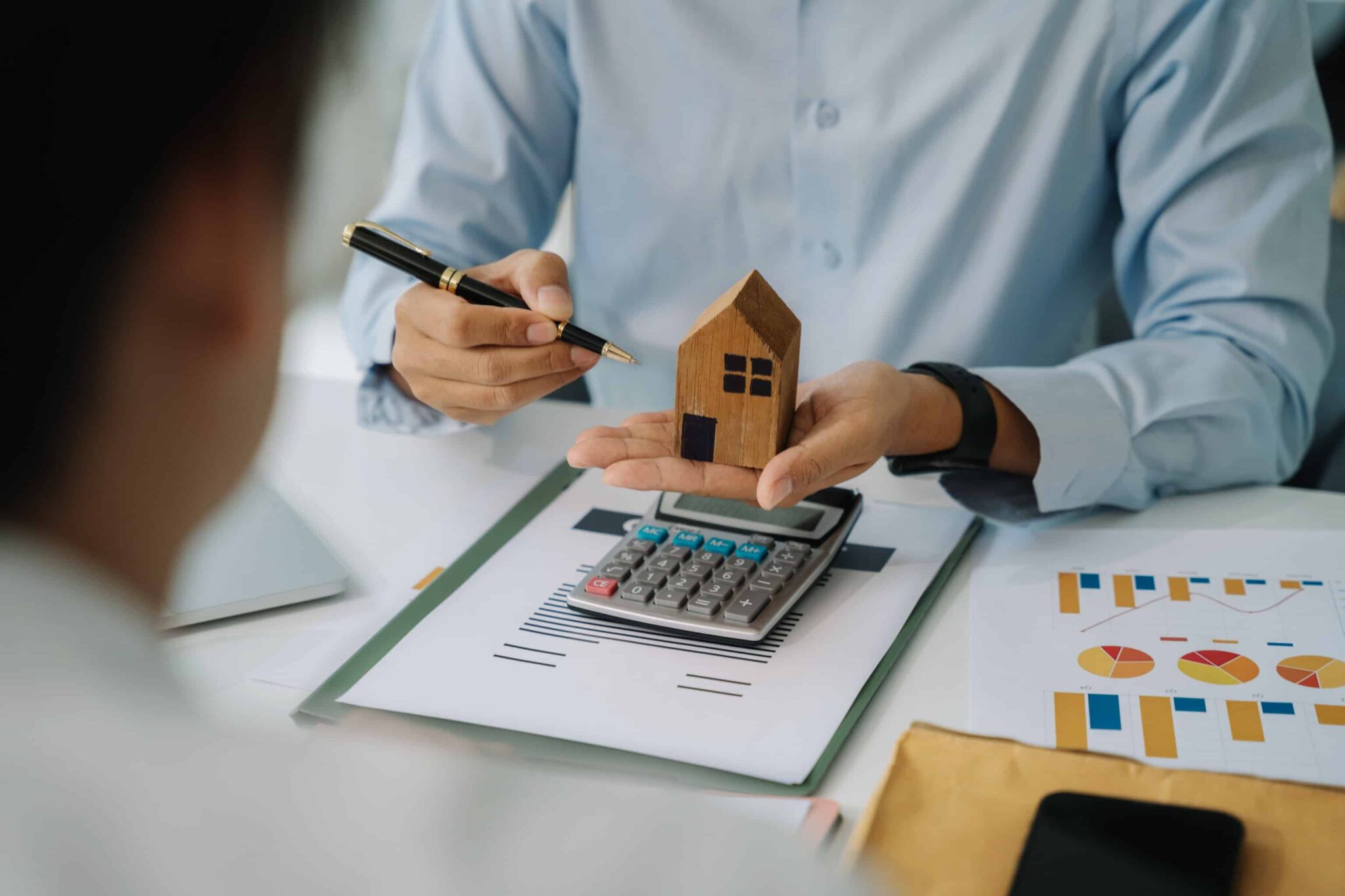 pessoa com uma casa de madeira na mão e calculadora a demonstrar qual a melhor opção para contratar um crédito habitação