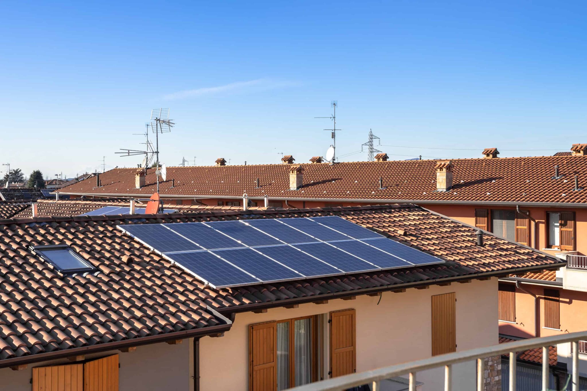 conjunto de casas, moradias, com uma delas de telhado vermelho onde estão instalados painéis solares