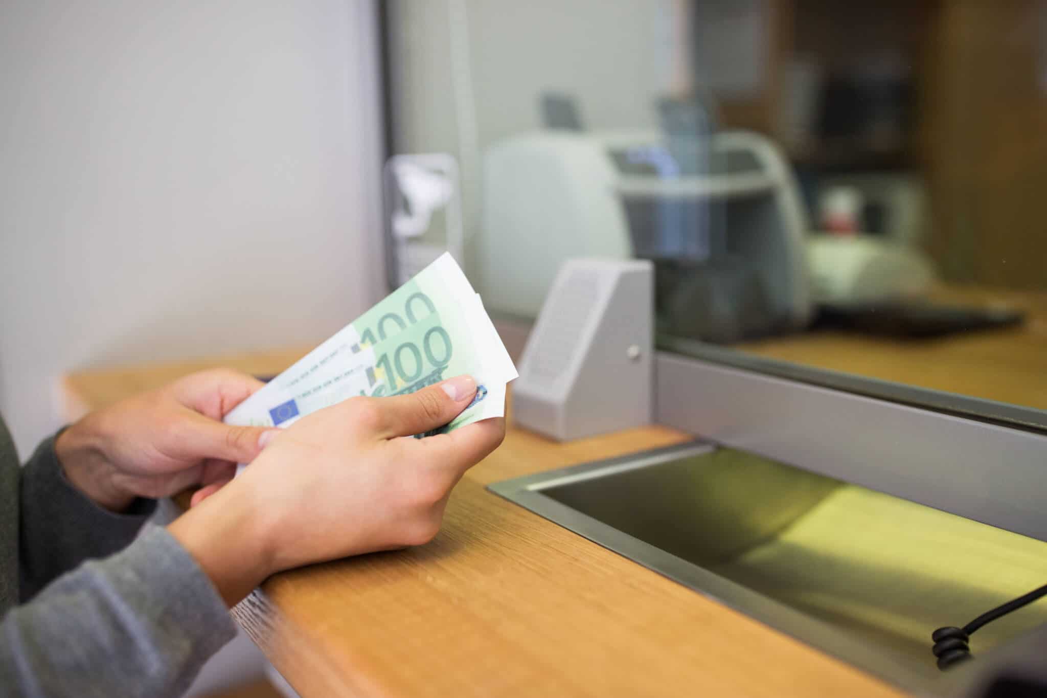 Pessoa com notas na mão a fazer depósito bancário