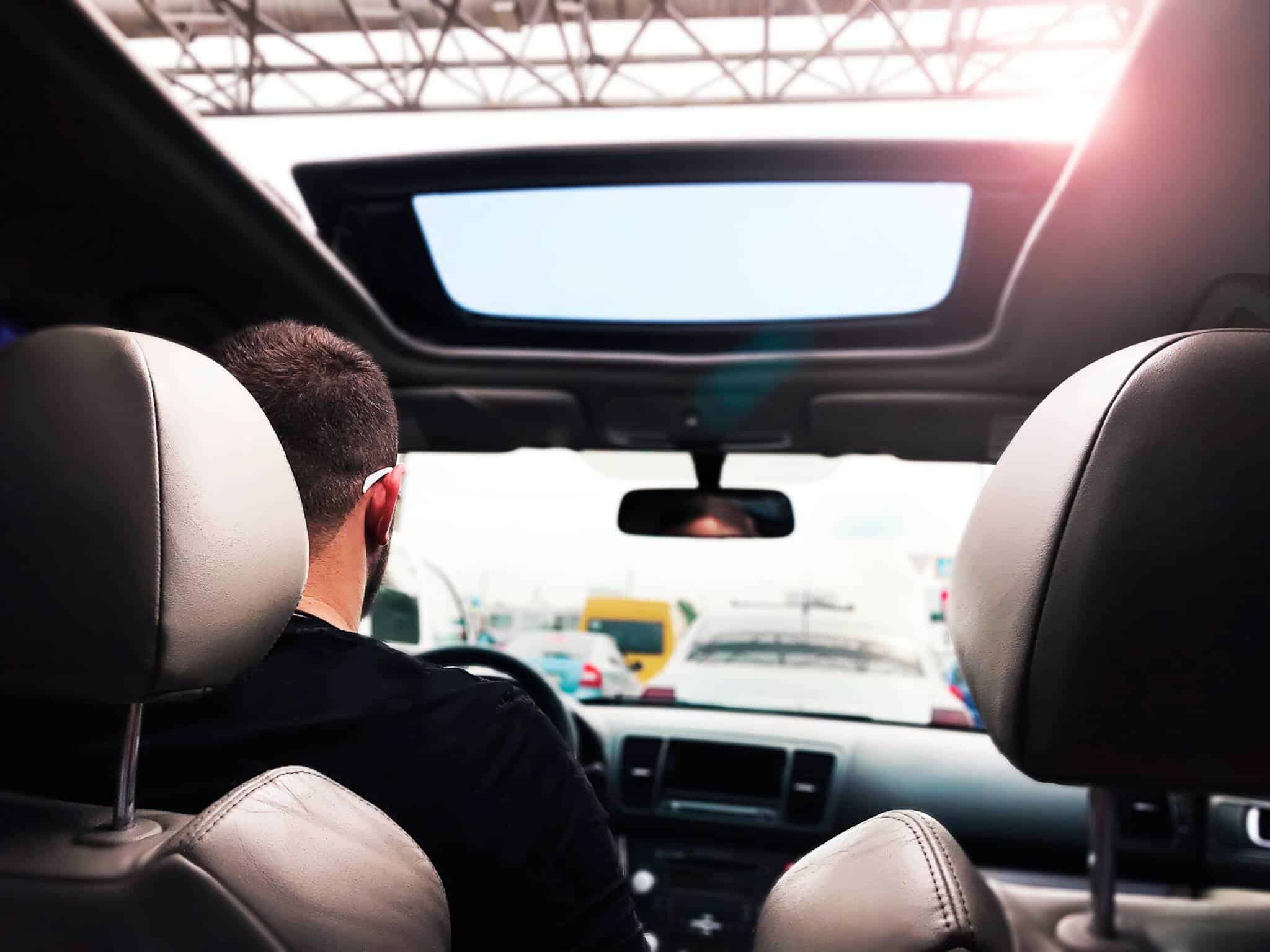 jovem rapaz a conduzir , com perpsetiva da frente vendo-se o vidro da frente carro, no qual o dístico do seguro já não é obrigatório