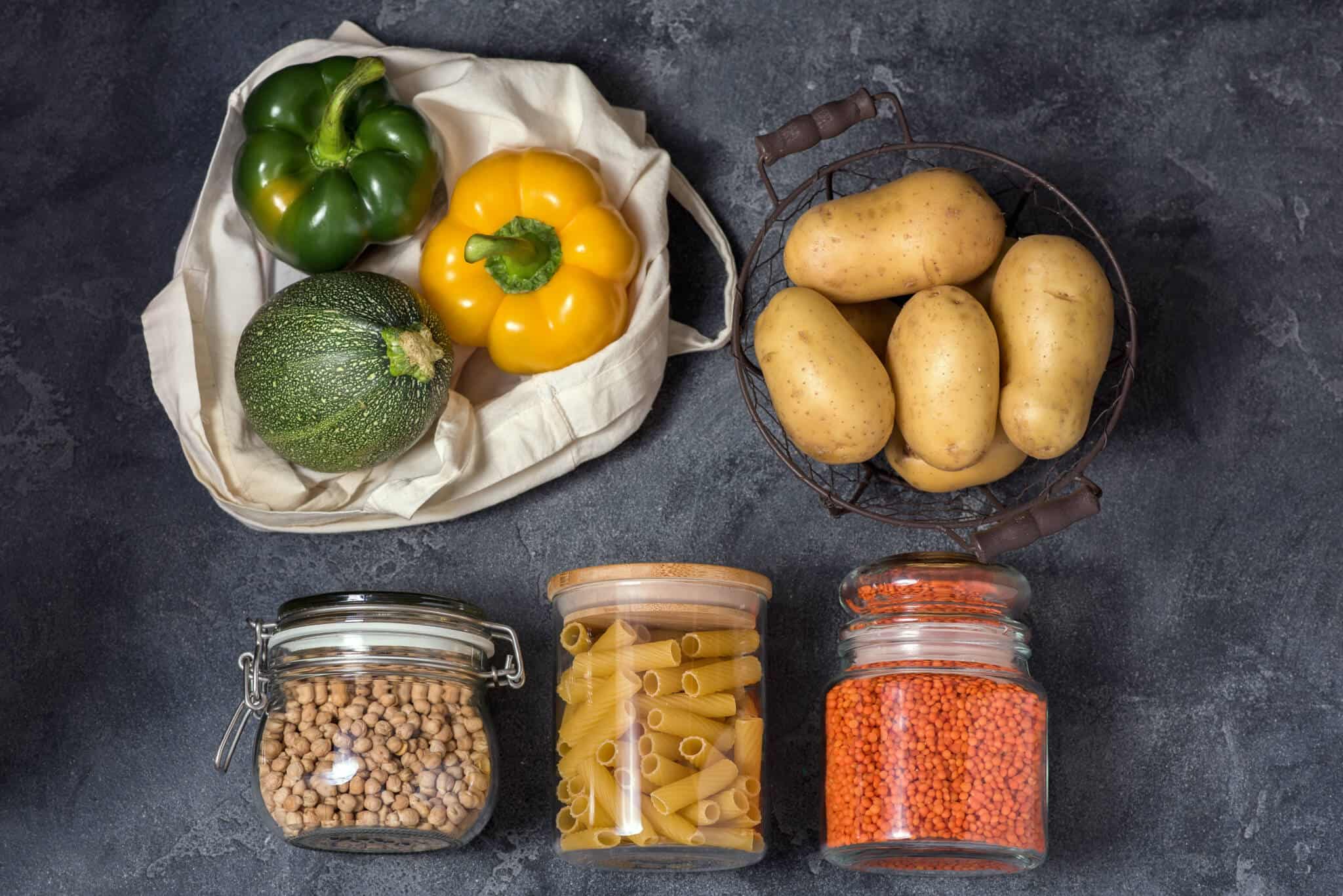 alimentos frescos e secos comprados a granel dispostos em pequenos grupos, em fundo cinzento, ilustram o movimento desperdício zero