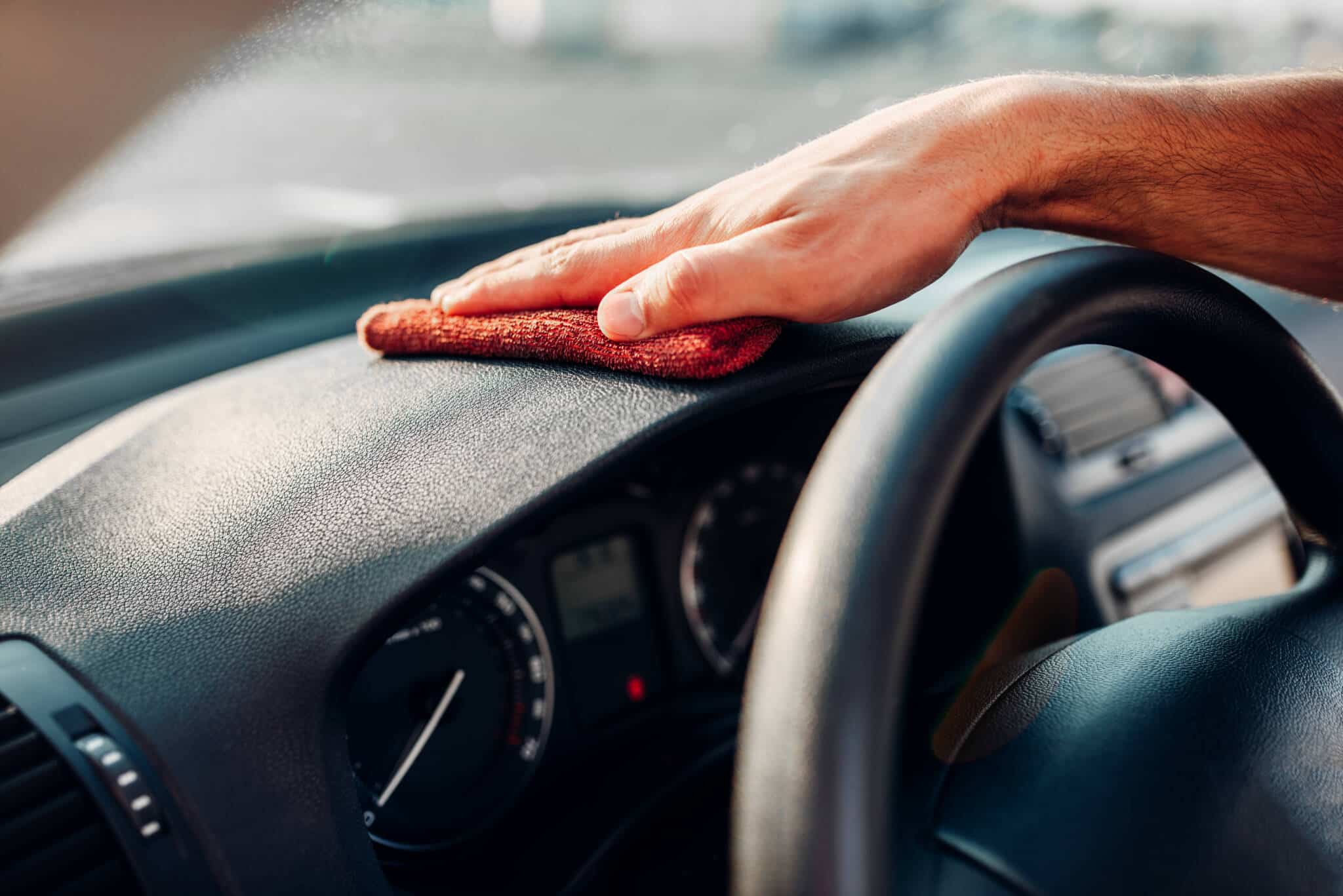 mão de homem com pano limpa o interior do carro , mostrando como poupar na manutenção do carro
