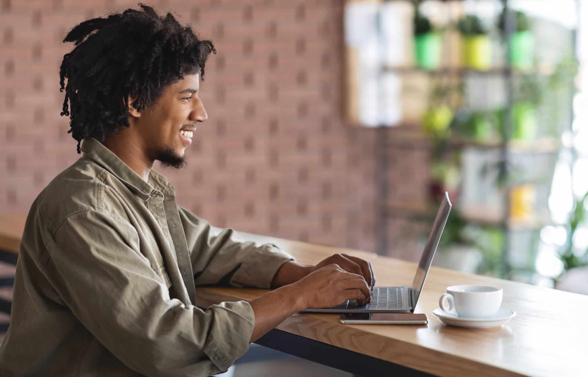 jovem rapaz , a usar o seu computador portátil, num ambiente relax de quem está em trabalho remoto