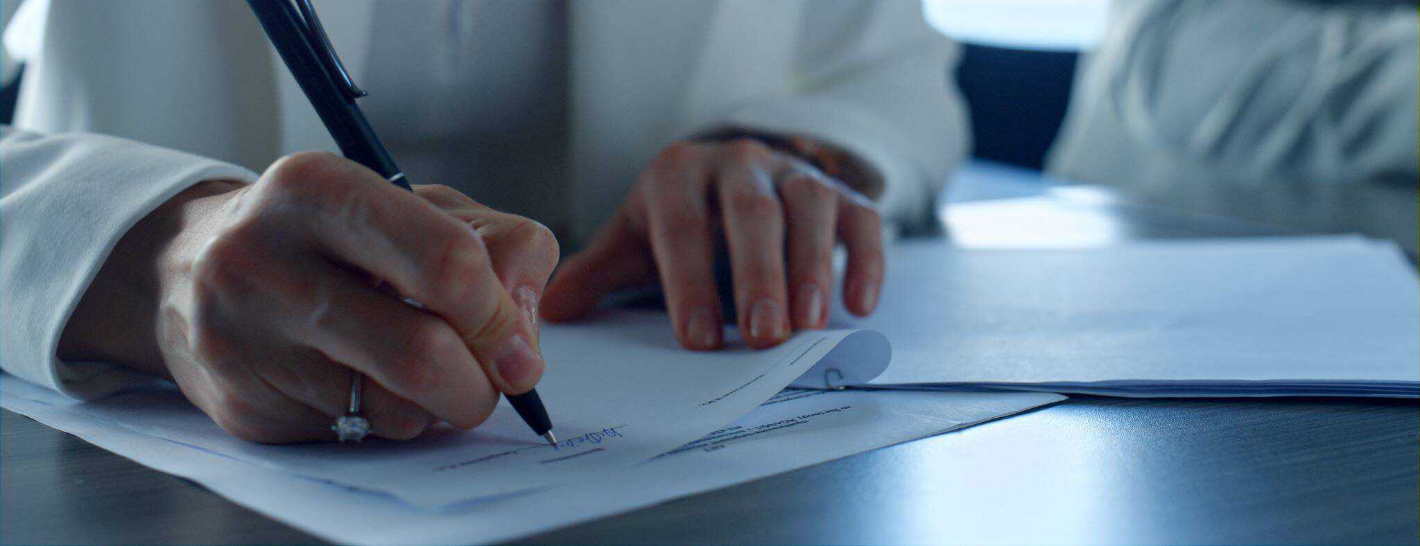 mulher com uma caneta não mão a assinar um contrato de mediação imobiliária