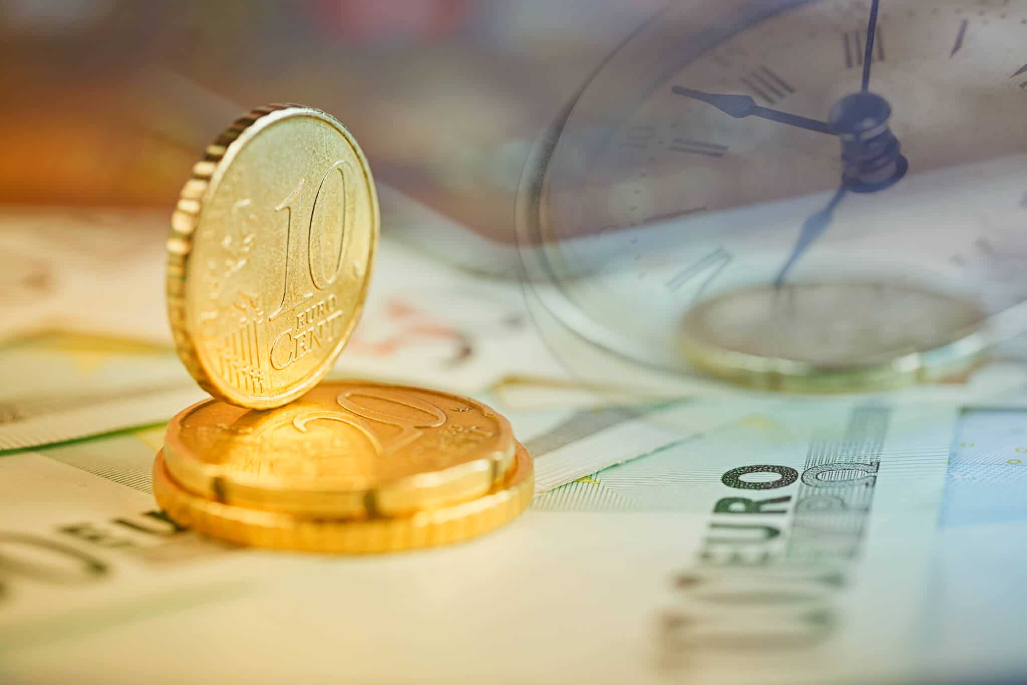 Moedas de euro empilhadas em cima de notas de euro, numa alusão à poupança e ao investimento