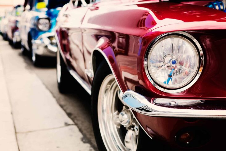 fila de carros clássicos, que devem ter um seguro específico, bem coloridos e alinhados junto ao um passeio