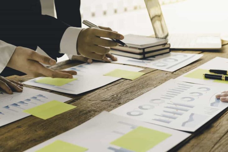 economistas a analisar documentos e gráficos