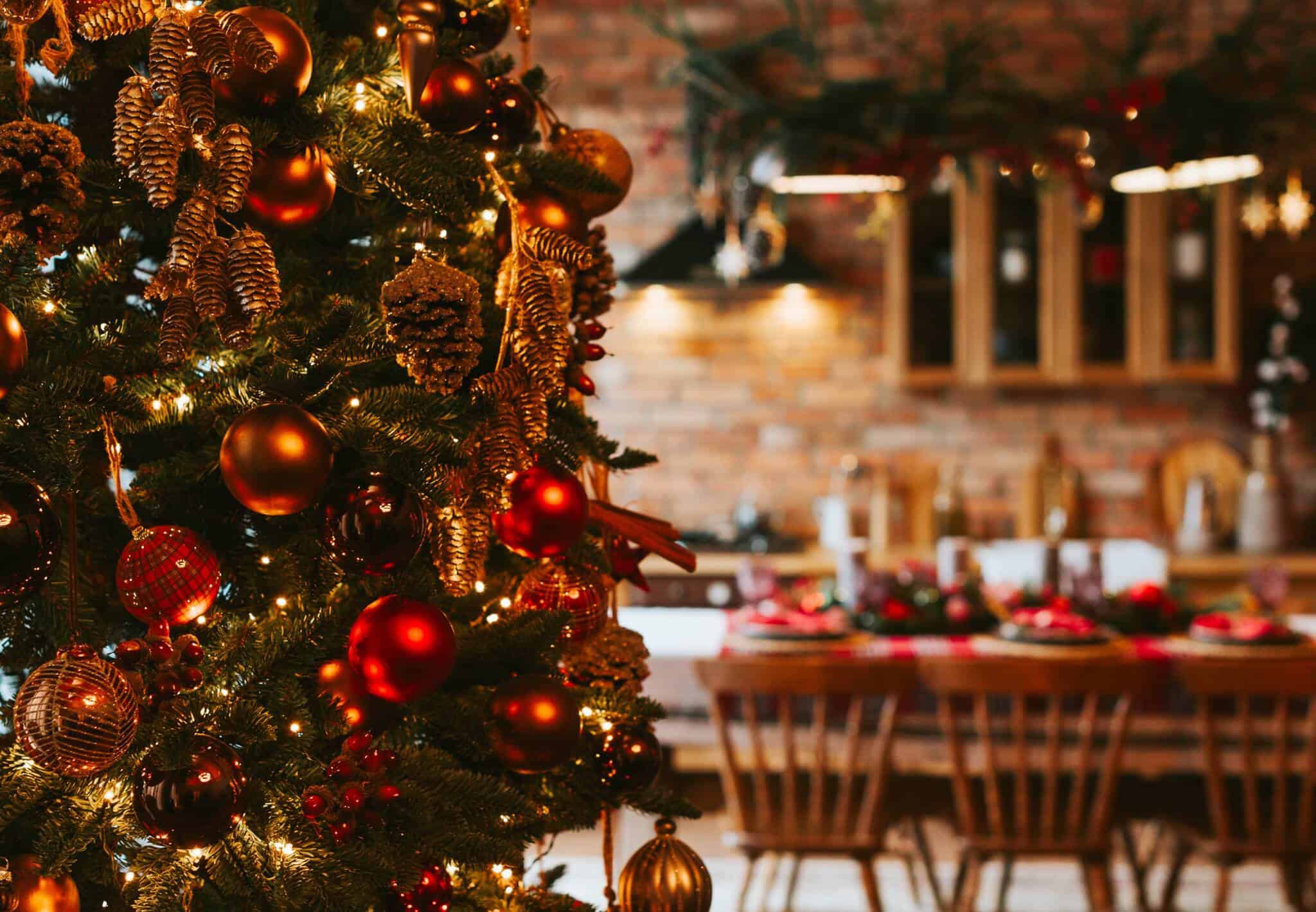 árvore de Natal em primeiro plano num ambiente de cozinha e sala com uma mesa da consoada preparada, celebrando o Natal sem desiquilibrar orçamento familiar