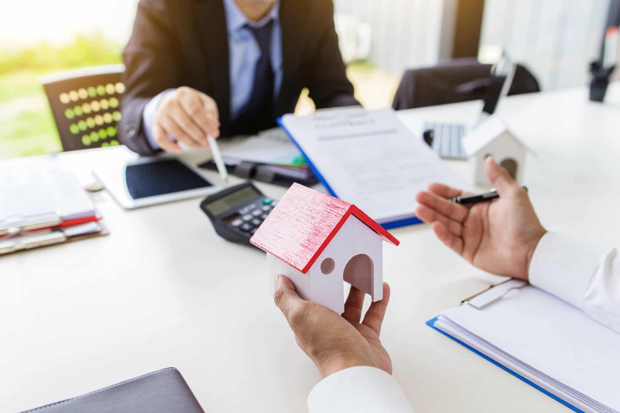 duas pessoas sentadas à secretária a fazer contas e a analisar se há direito à isenção das mais-valias imobiliárias