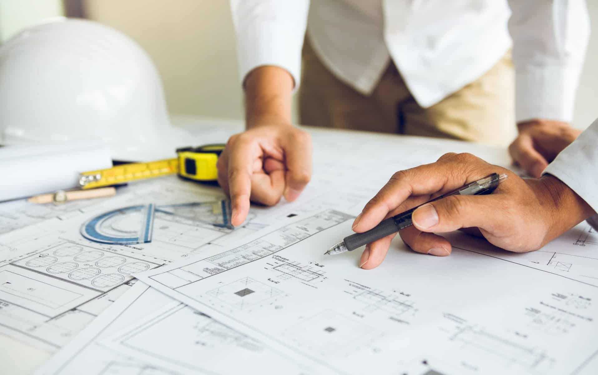 imagem de uma projeto de obras - planta de uma casa - duas pessoas a apontar para o projeto