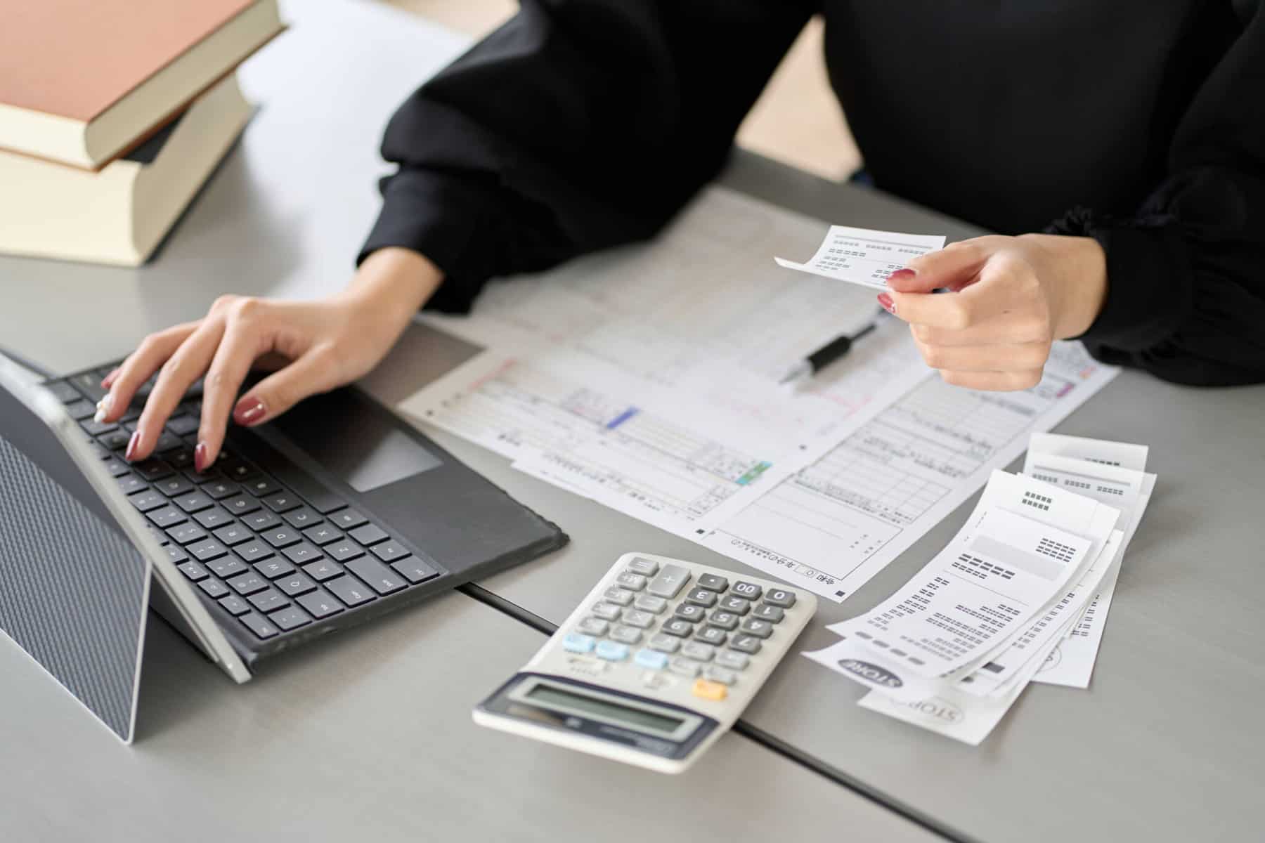 mão de jovem mulher introduz no pc dados retirados das faturas para preparar o IRS automático