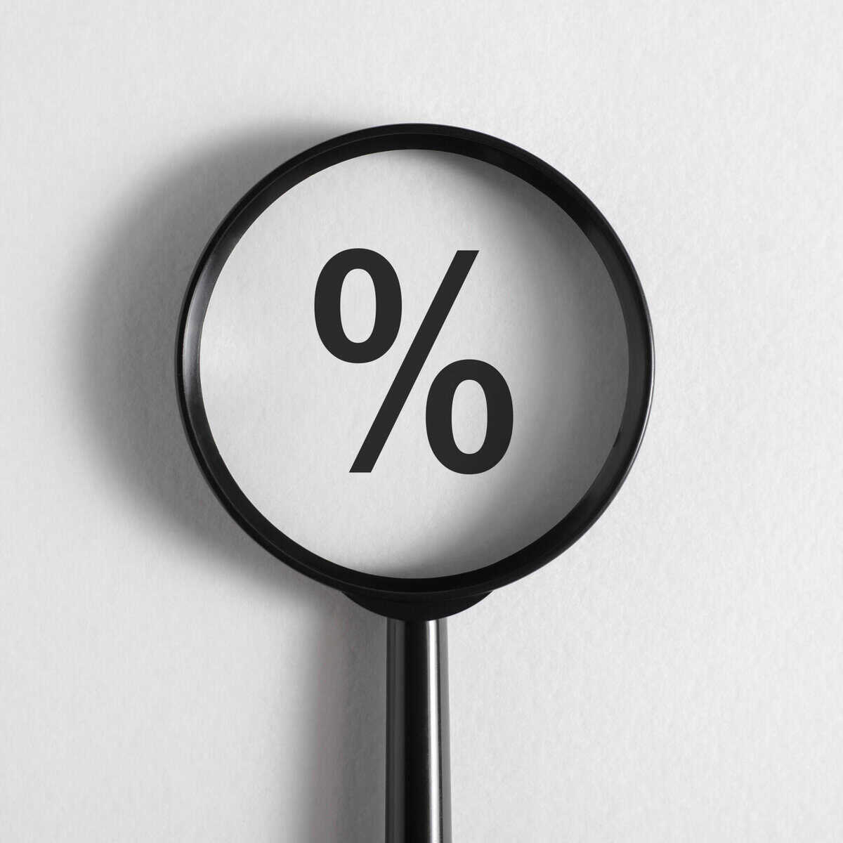 Lupa colocada em cima do símbolo de percentagem, que está relacionado com as taxas de juro e a sua evolução