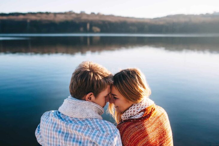 Casal jovem com as testas juntas e a sorrir, a evocar casados e unidos de facto